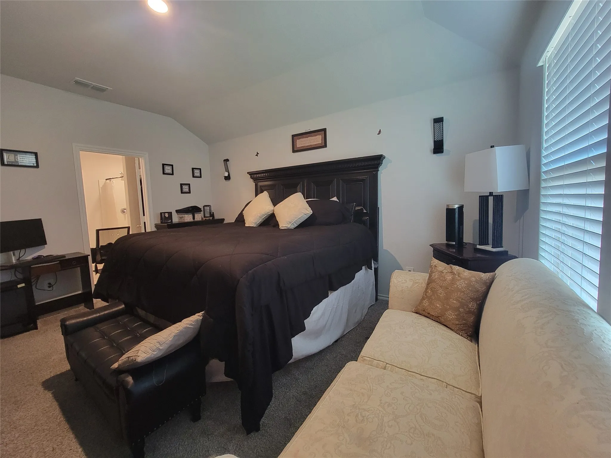 Vaulted ceiling featuring a ceiling-mounted light fixture, carpeted flooring, and window with horizontal blinds