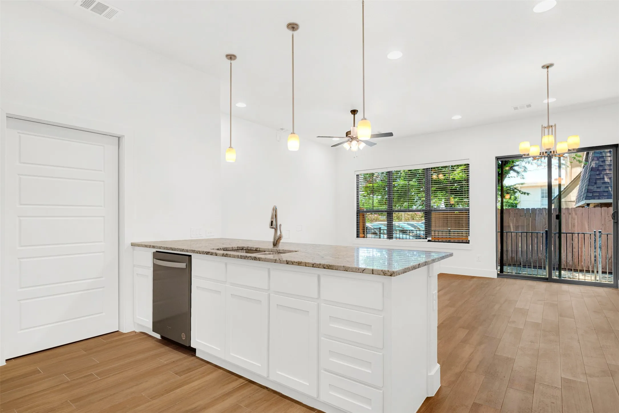 view of kitchen bar adjacent to range & refrigerator. Pantry opens with Sliding doors to the left of dishwasher.   See private patio with iron fence thru sliding patio doors.