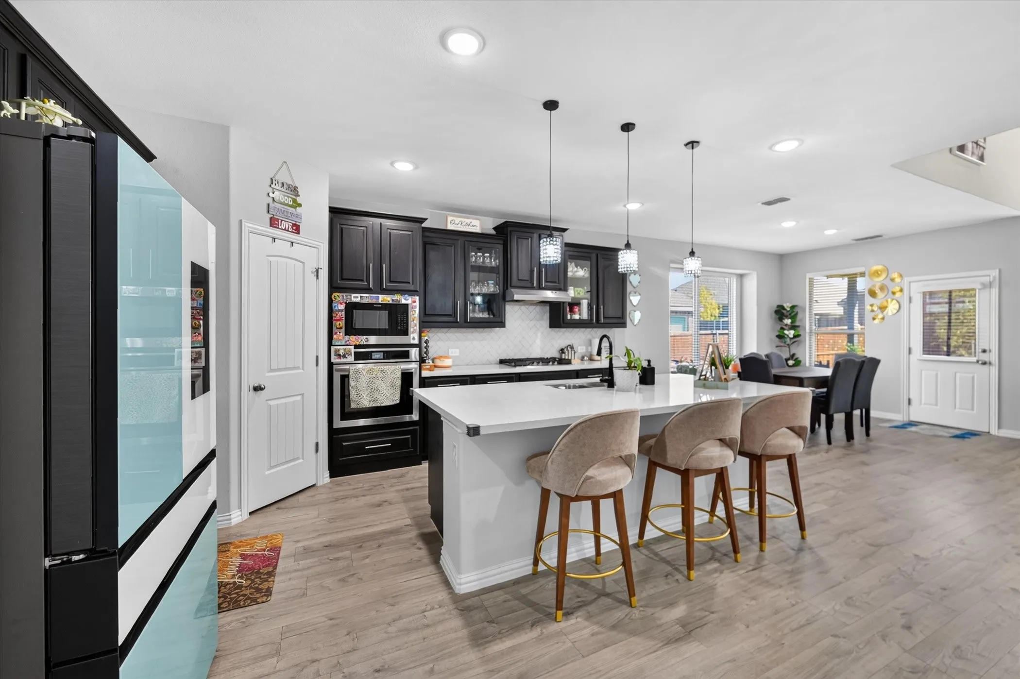 White quartz kitchen island with pendant lighting, dark wood-finish cabinetry, built-in double oven, and wood-finish flooring