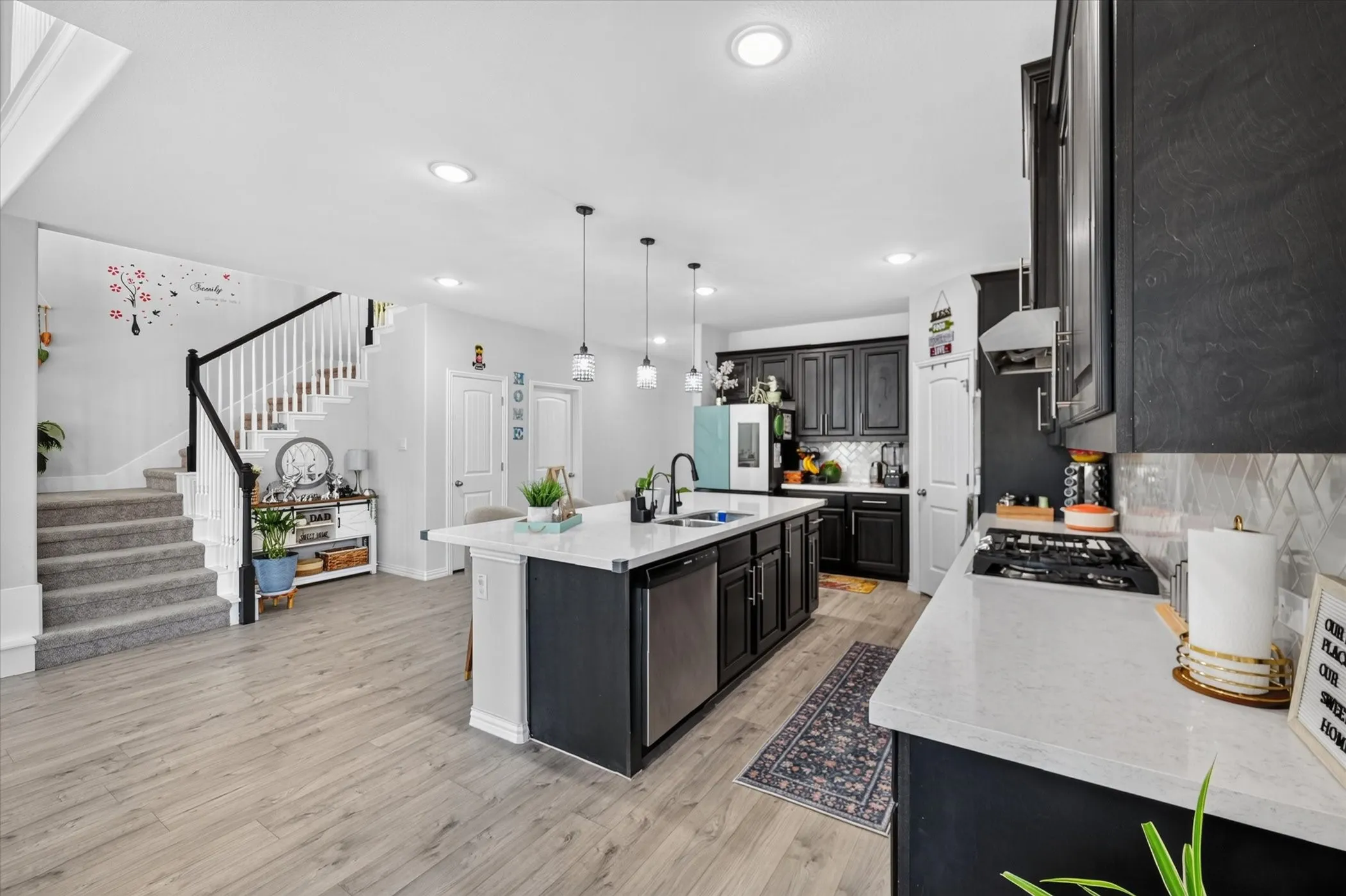 Open-concept kitchen with dark cabinetry, white countertops, and a tile backsplash