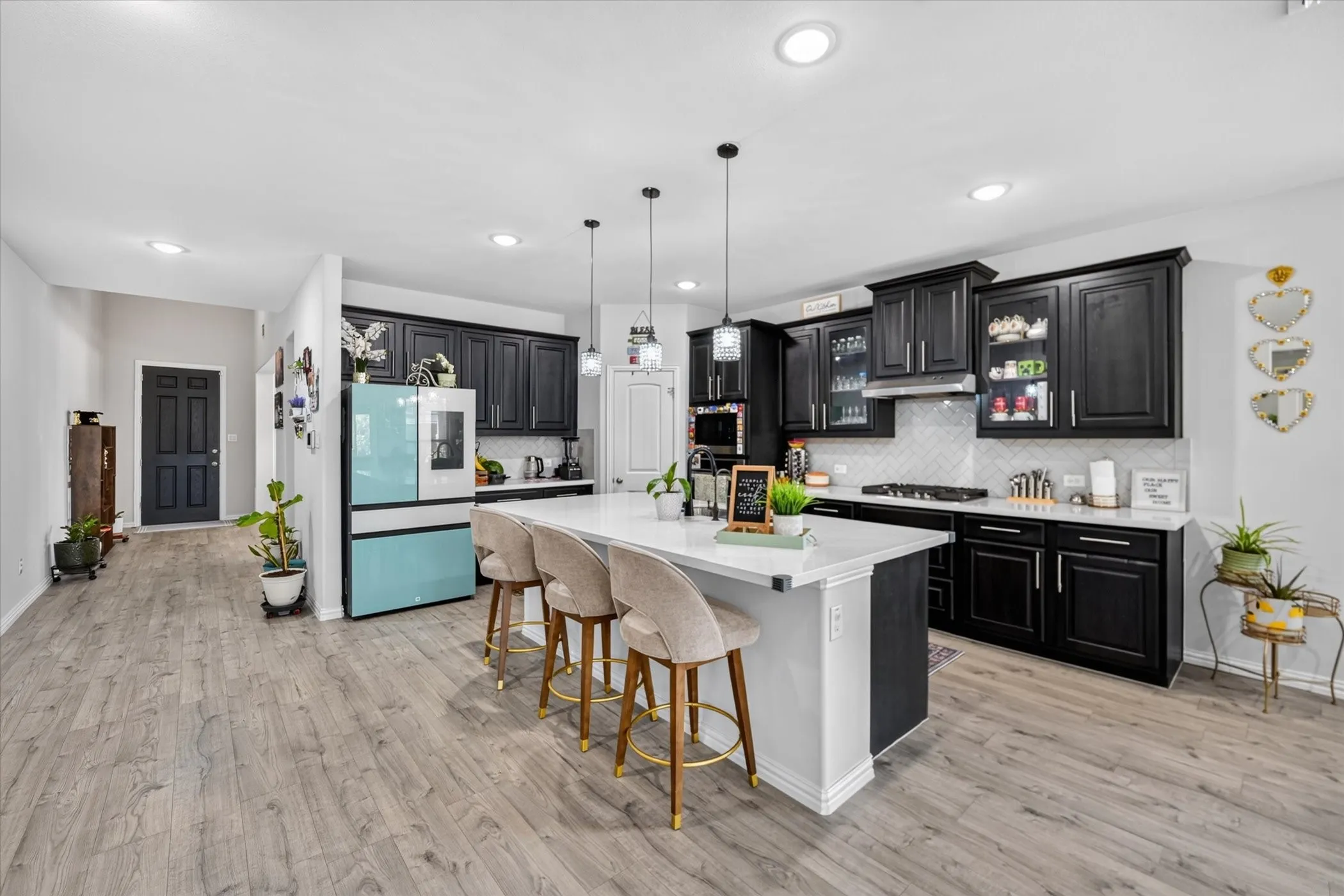 Kitchen featuring dark cabinetry, white countertops, a central island with seating, a gas range, and a tile backsplash