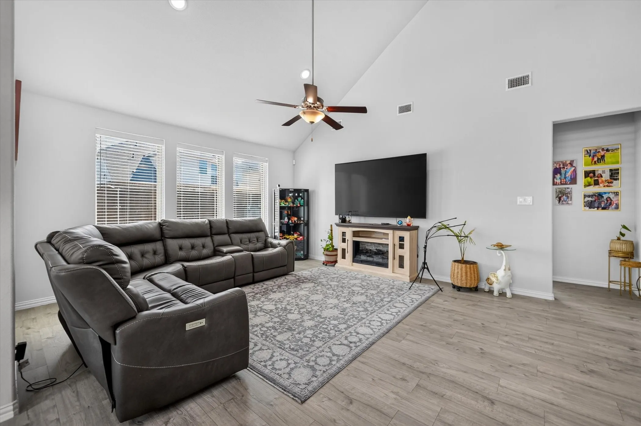 Vaulted ceiling, recessed lighting, ceiling fan, wood-finish flooring, and multiple windows with blinds