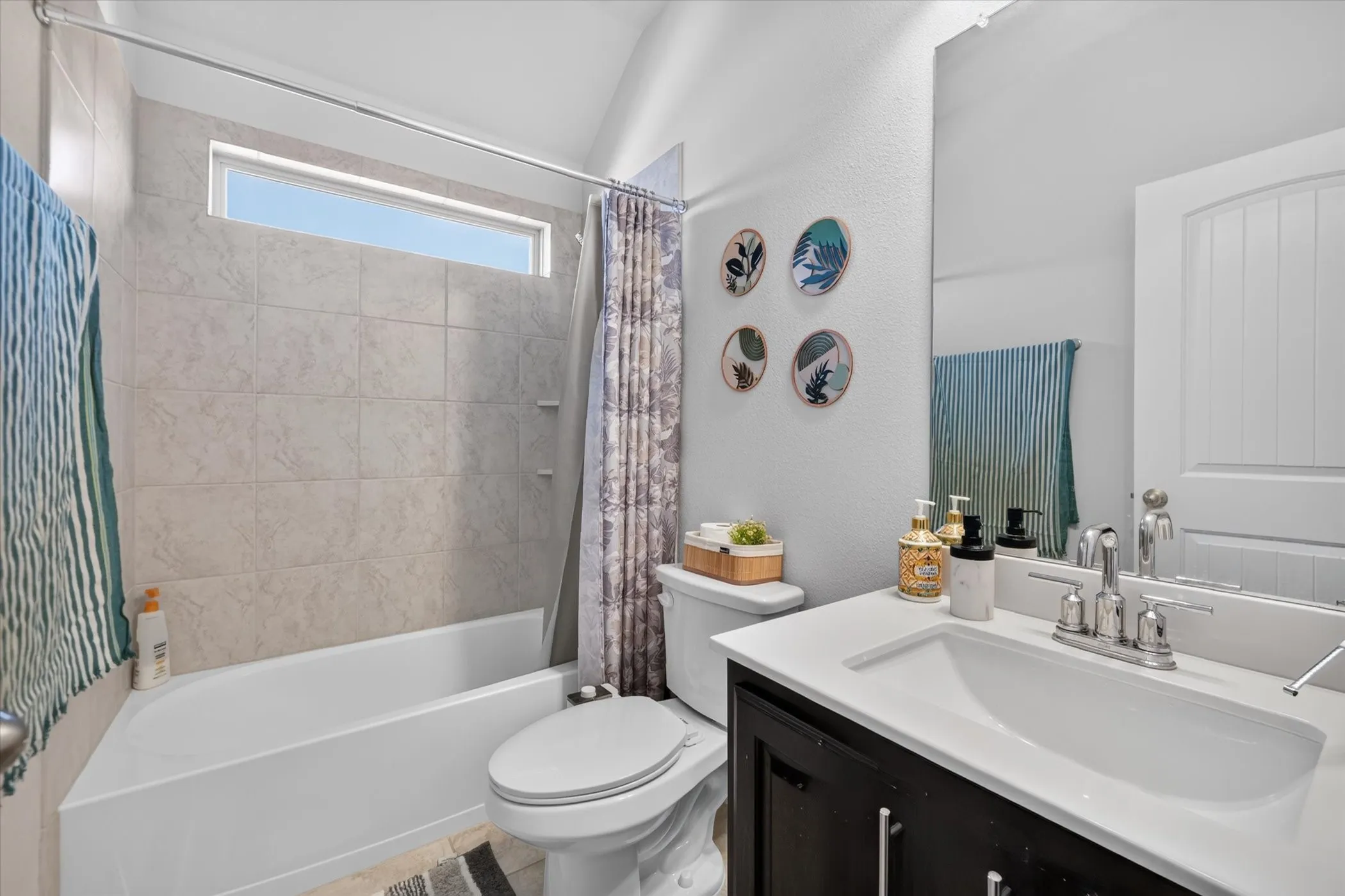 Tub/shower combination with tile surround, high transom window, and a single vanity with a rectangular undermount sink