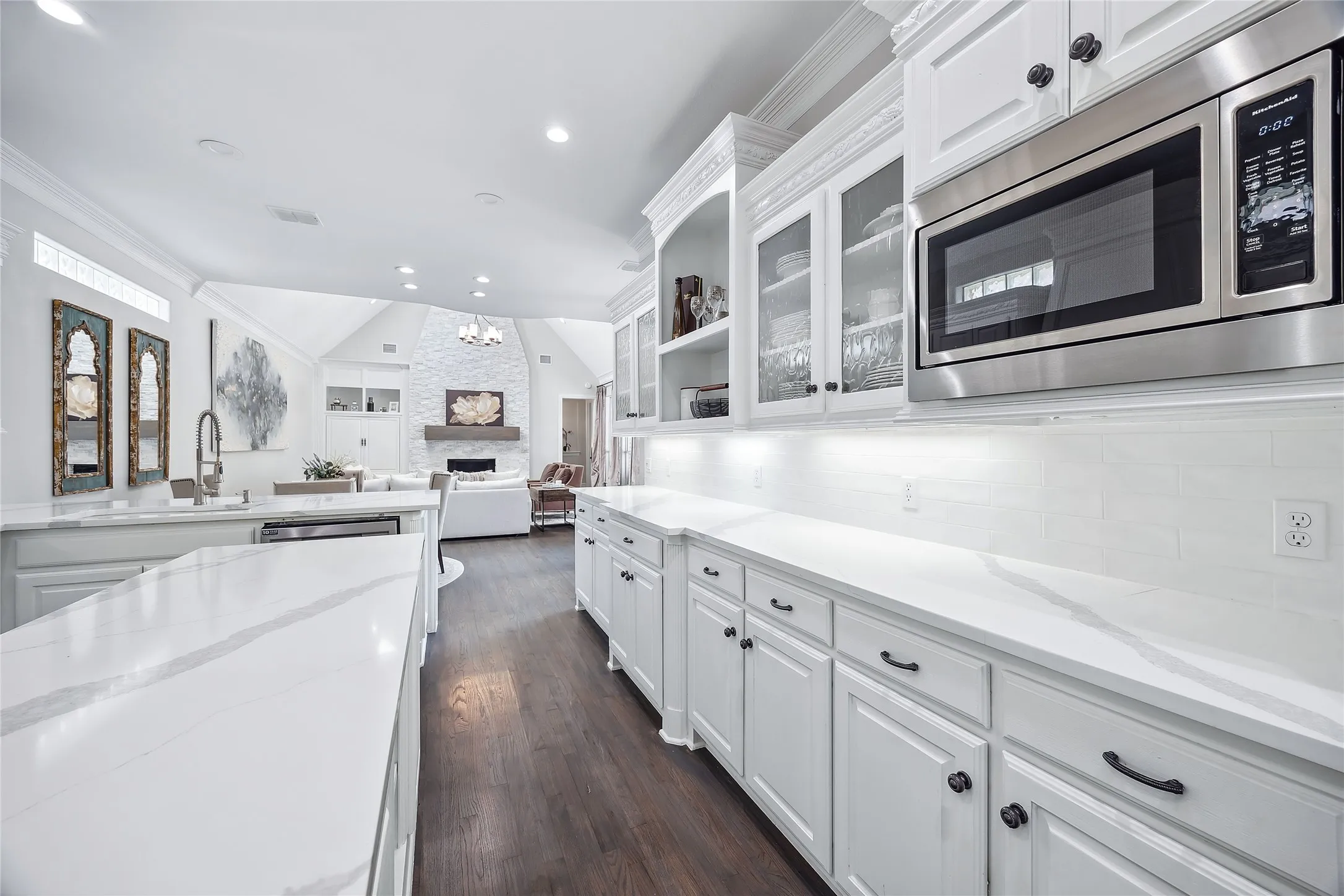 White cabinetry with black hardware, stainless steel microwave, white countertop surfaces, wood-finish flooring, and recessed lighting