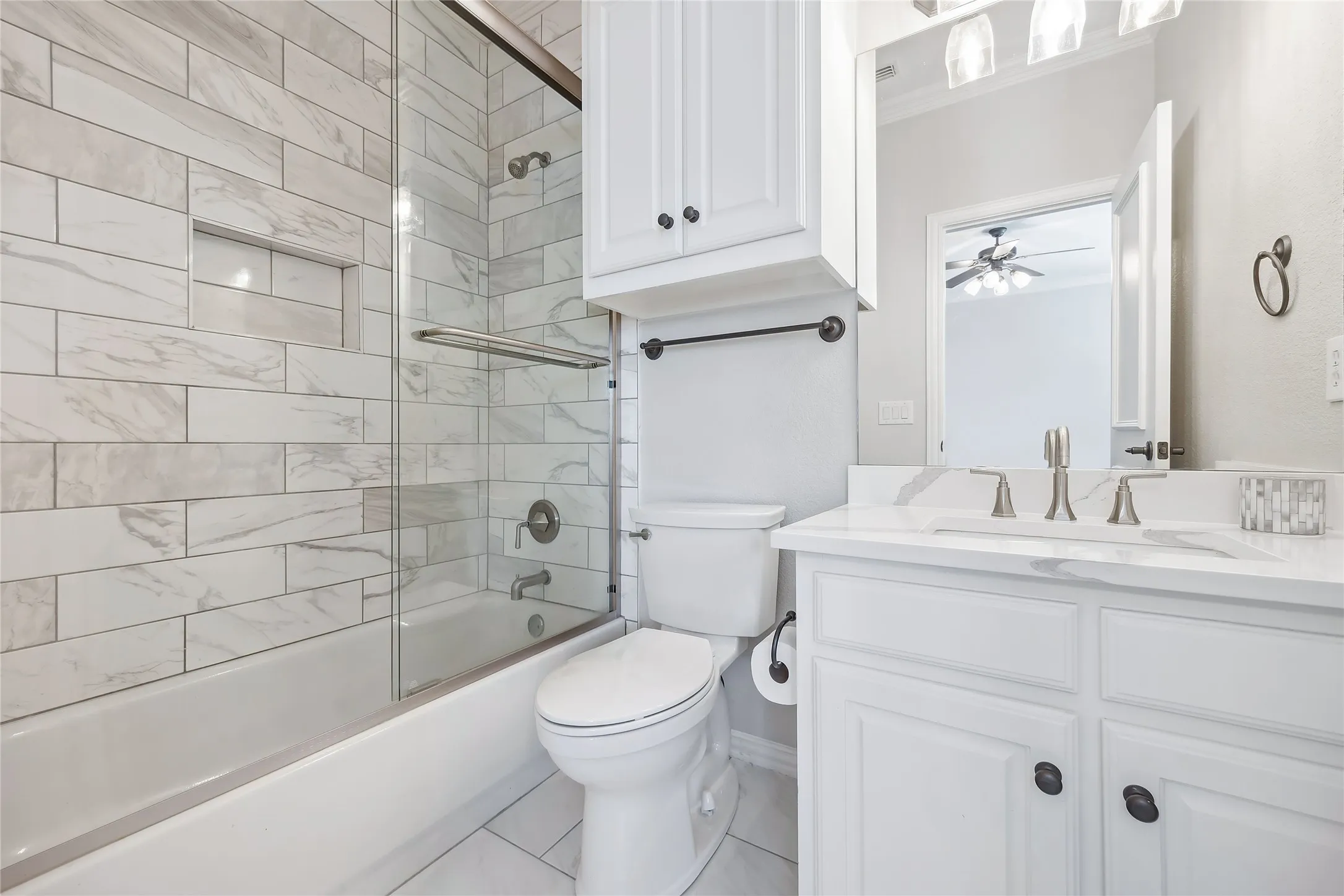 Shower-tub combination with a glass enclosure, an in-wall niche, and subway tile surround