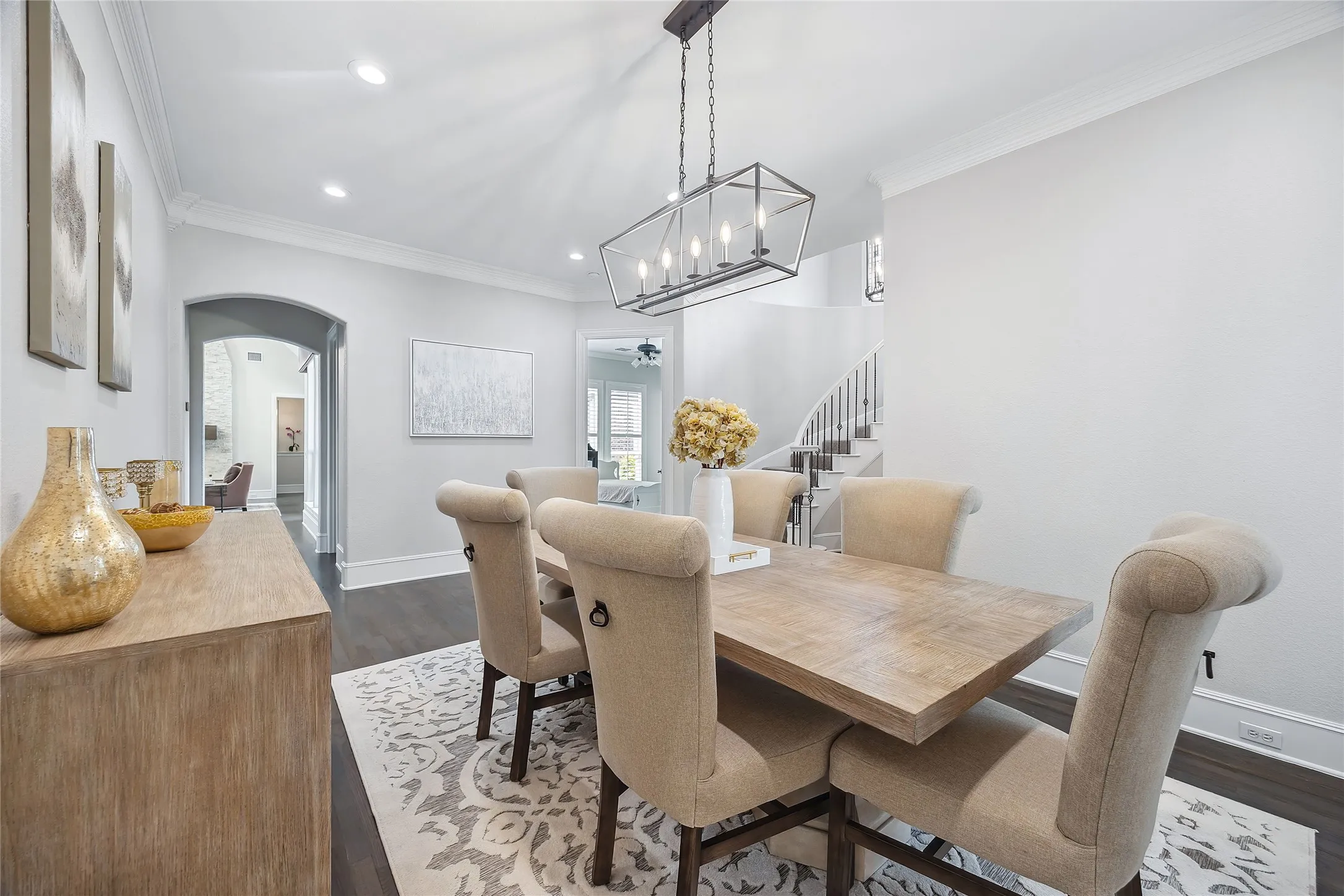 Recessed lighting, crown molding, wood-finish flooring, staircase with white risers and dark treads, and a rectangular chandelier