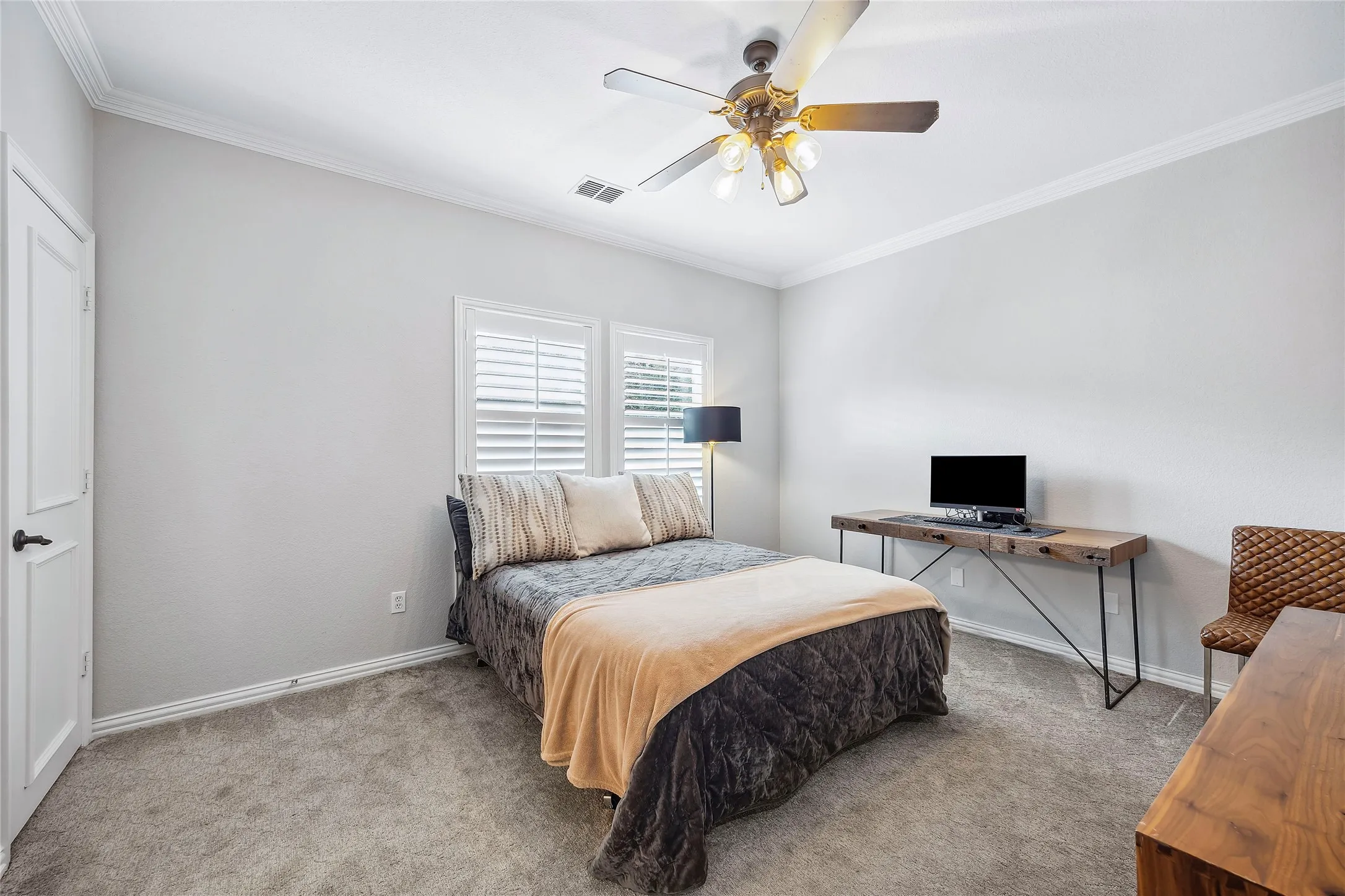 Crown molding, white plantation shutters, ceiling fan with integrated lighting, gray carpeting, and a white paneled door