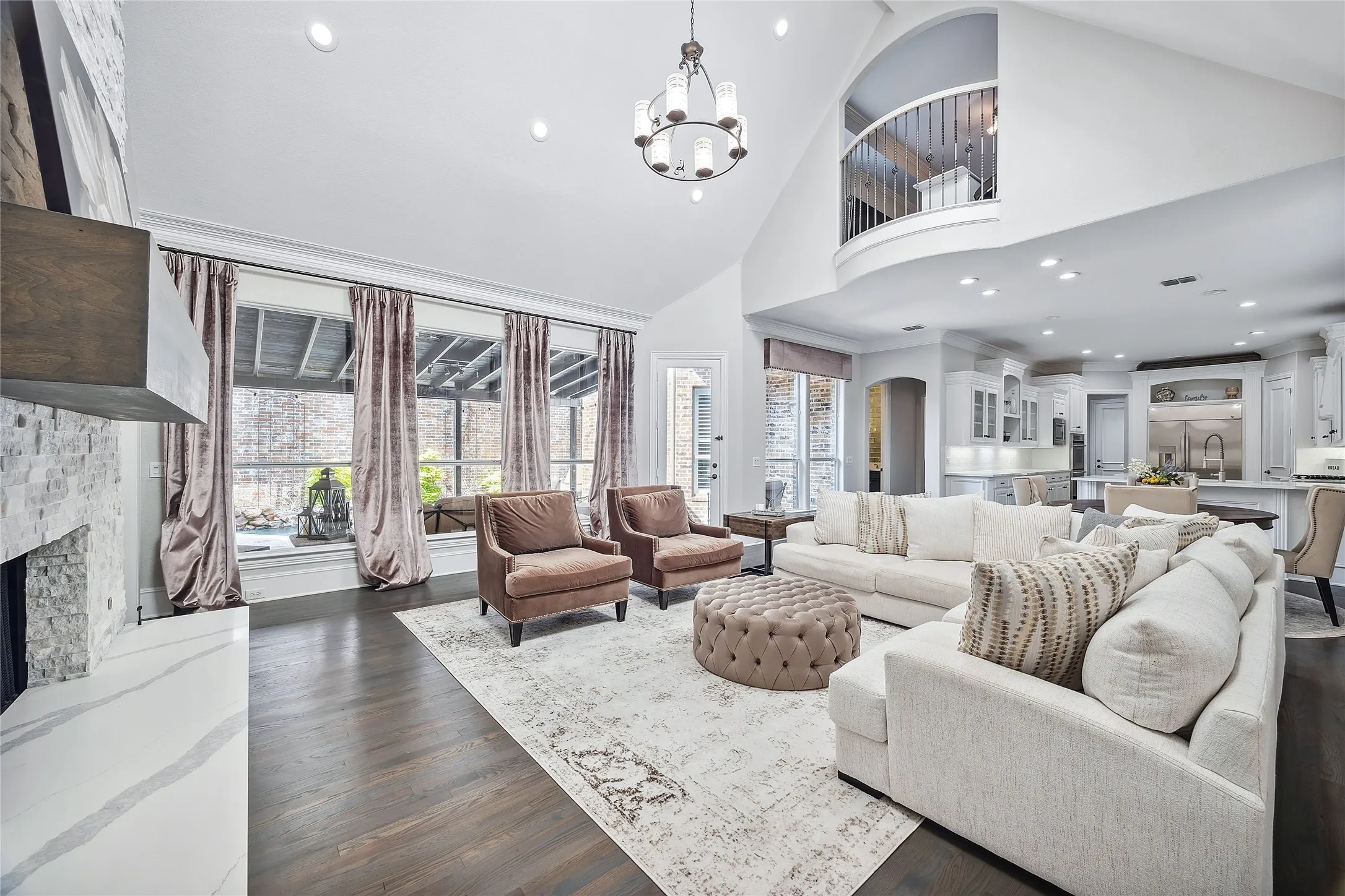 Vaulted ceiling, recessed lighting, wood-finish flooring, stone-clad fireplace, and an upper-level balcony