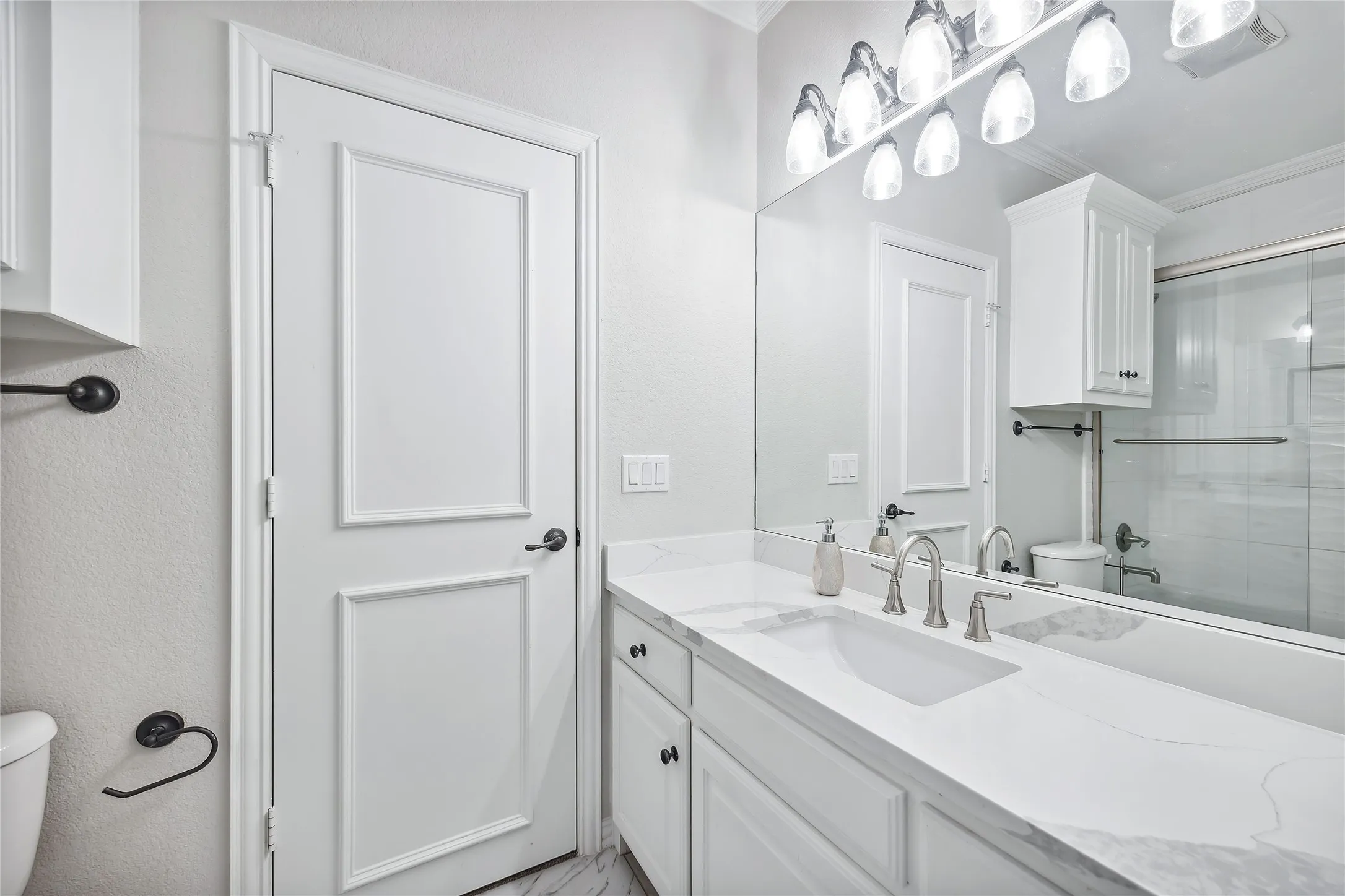 Vanity with an integrated rectangular sink, brushed nickel faucet, full-width mirror, and overhead vanity lighting