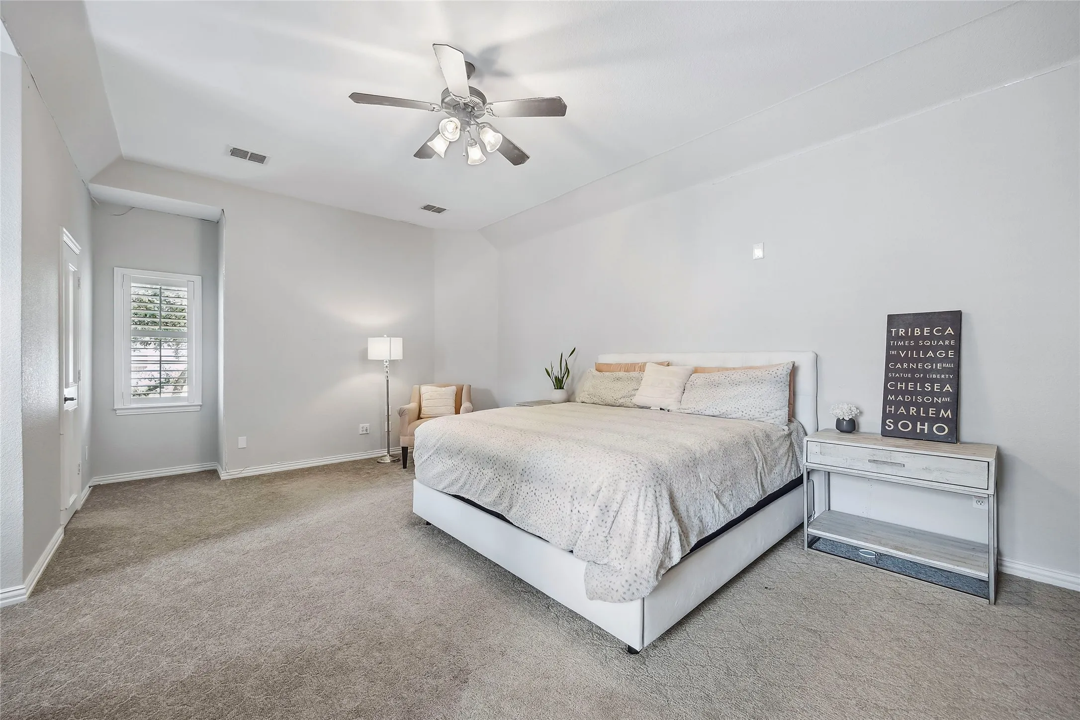Vaulted ceiling, ceiling fan with integrated lighting, window with plantation shutters, light gray wall paint, and gray carpet