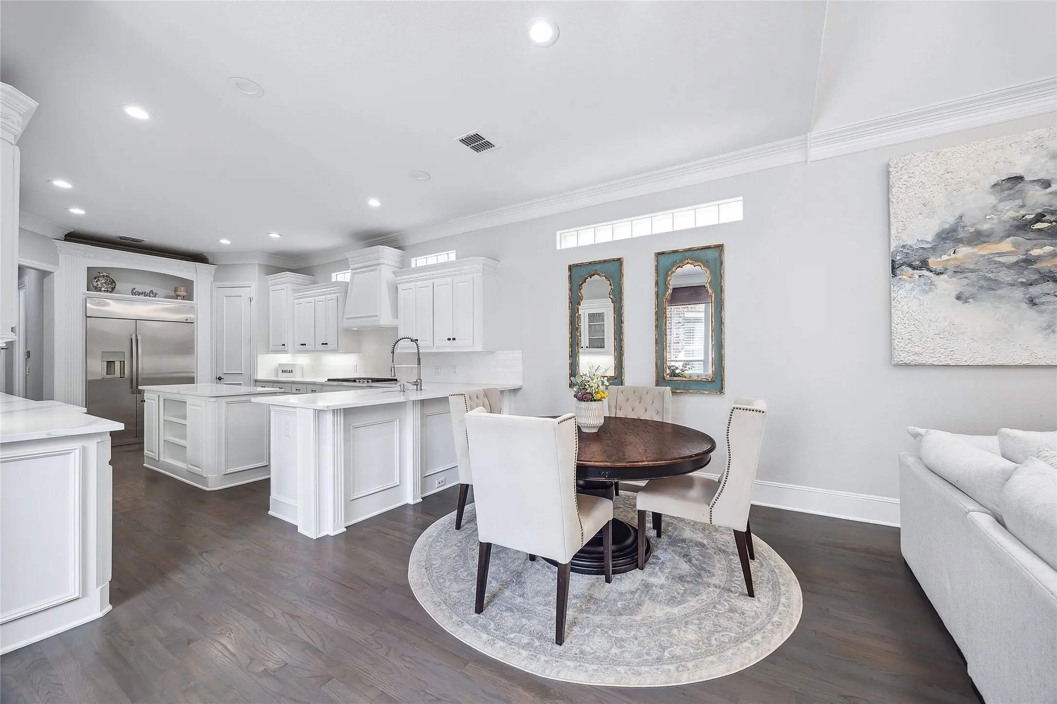 Spacious kitchen featuring white cabinetry, stainless steel appliances, and a central island with countertop seating