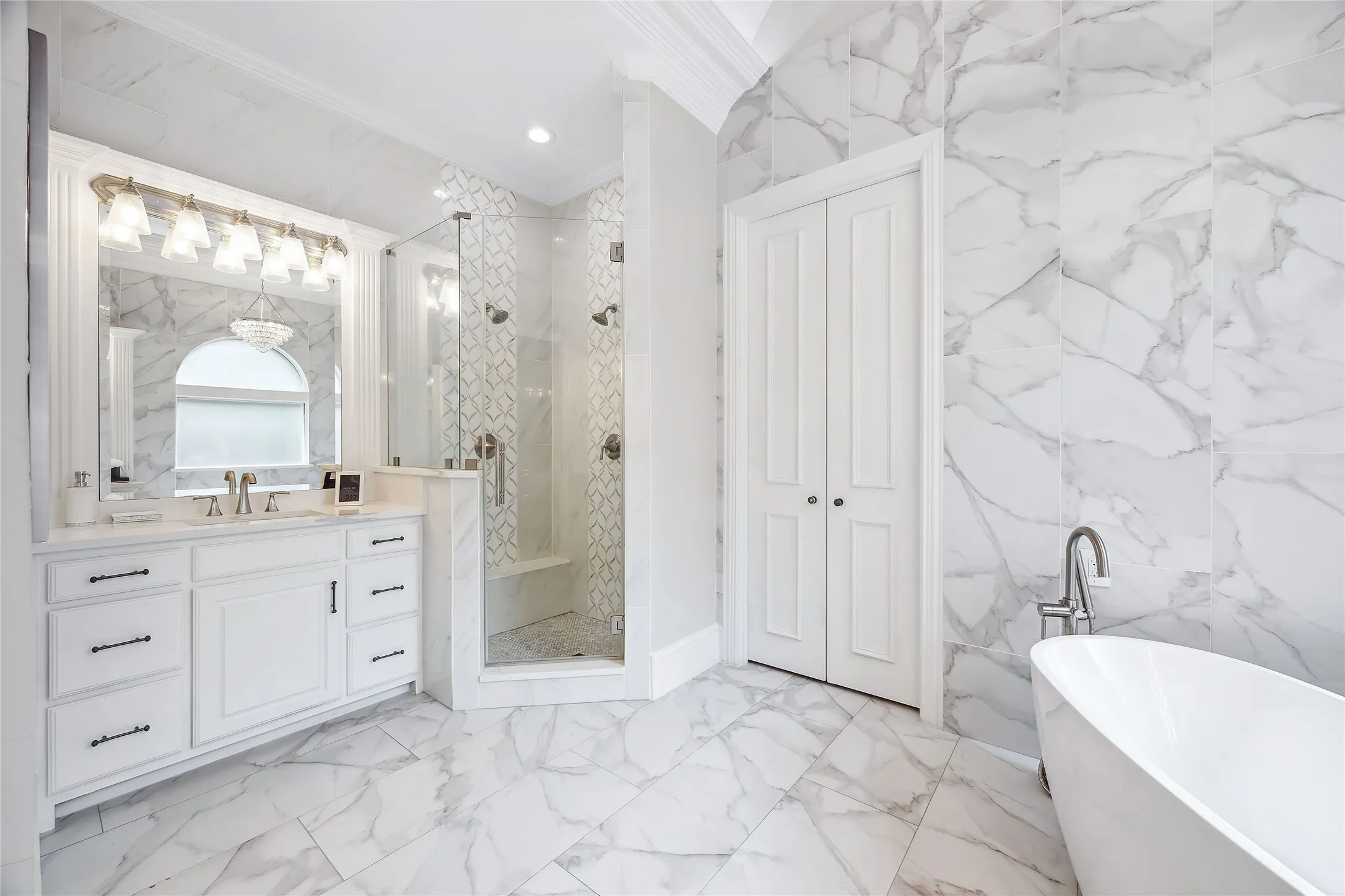 Spacious bathroom featuring a freestanding soaking tub, expansive walk-in shower, dual vanity, and marble-look tile flooring