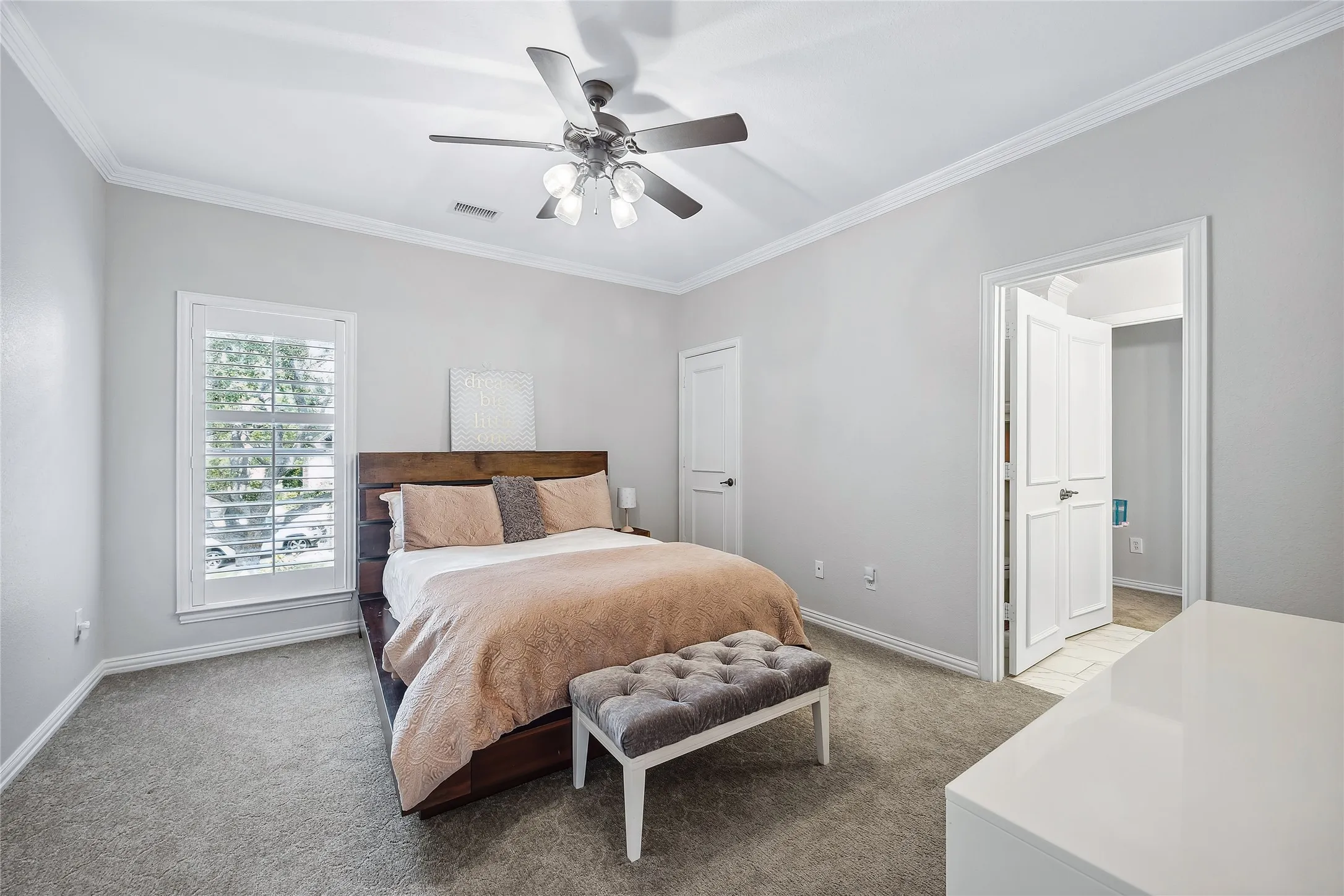 Vaulted ceiling, ceiling fan with integrated lighting, window with plantation shutters, light gray wall finish, and gray carpet