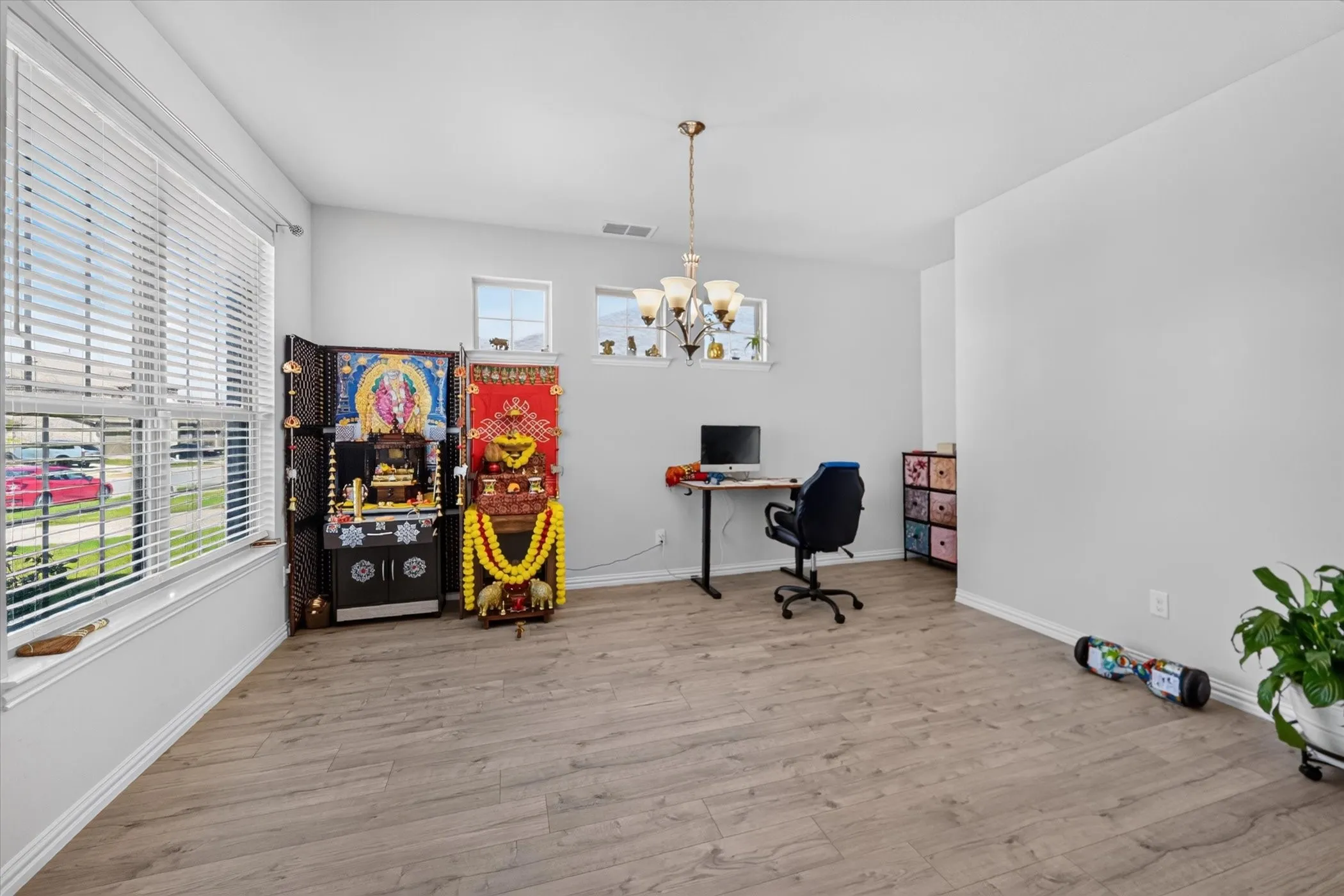 Wood-finish flooring, multiple windows with blinds, recessed ceiling, and a ceiling-mounted light fixture
