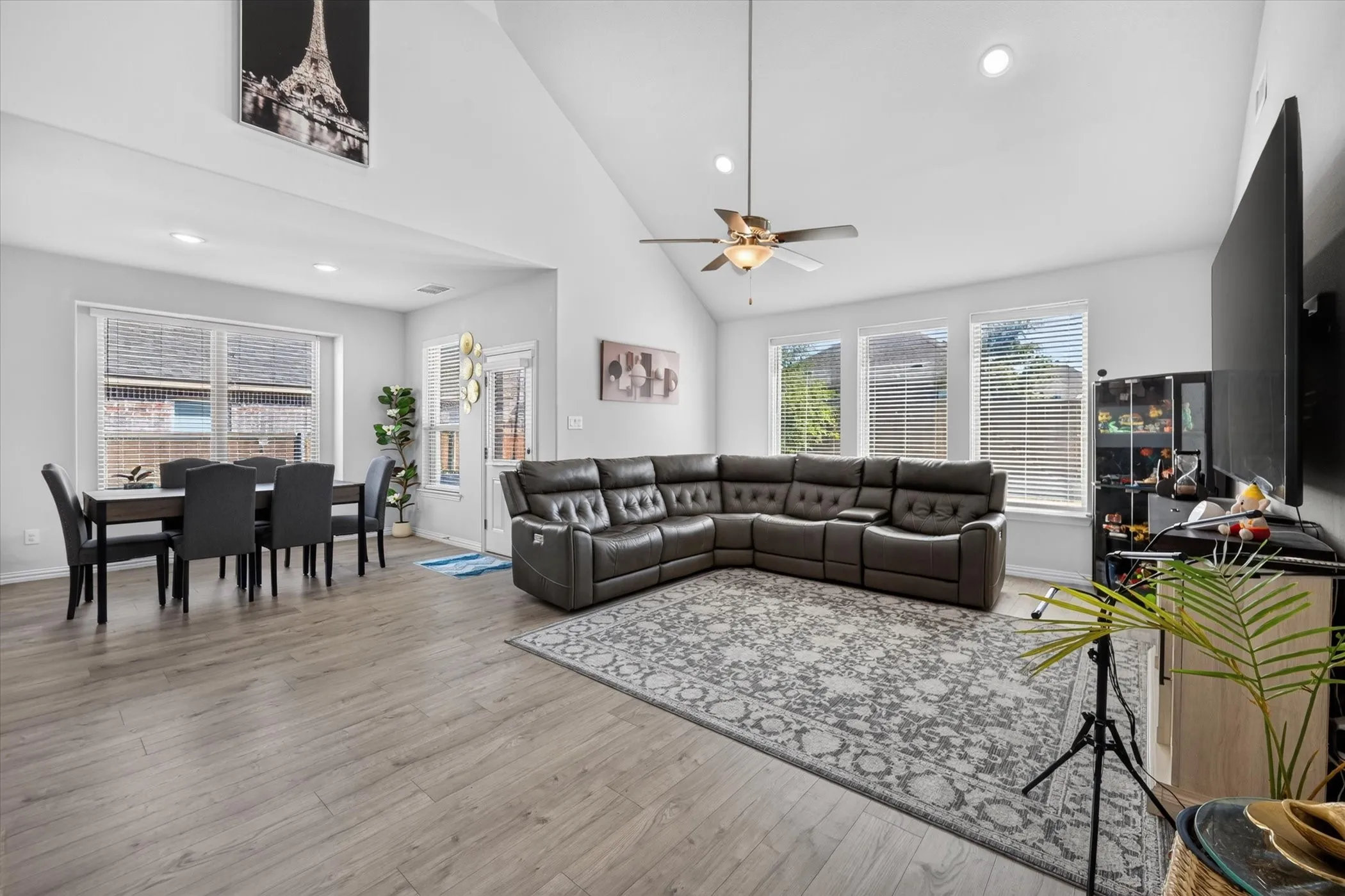 Vaulted ceiling with a ceiling fan, recessed lighting, wood-finish flooring, and multiple windows