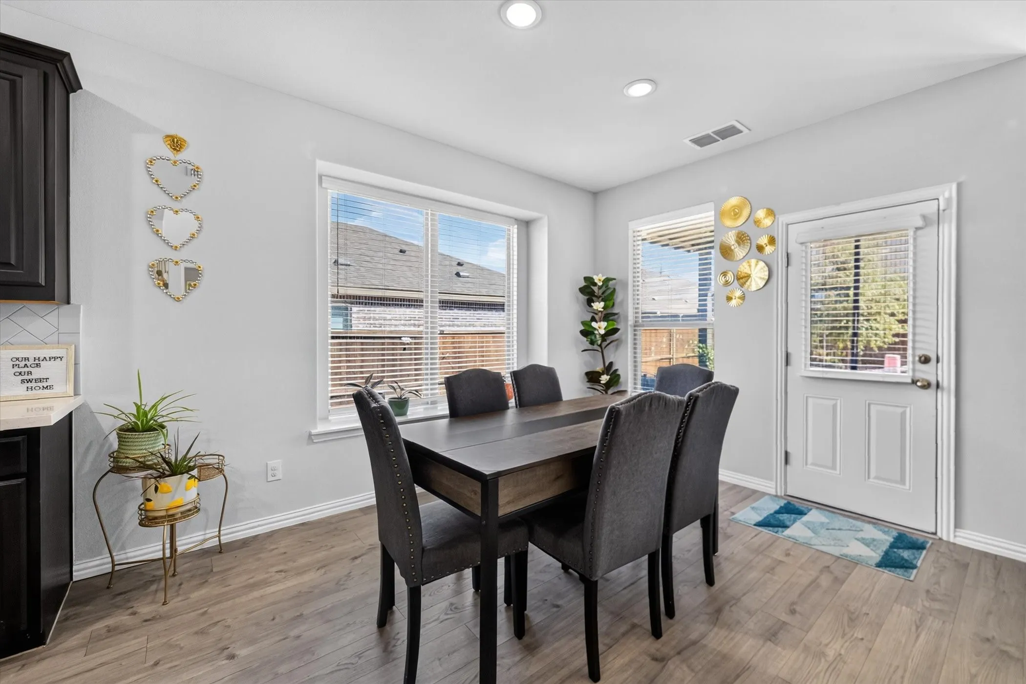 Recessed lighting, wood-finish flooring, multiple windows with blinds, white trim, and a white door with a window