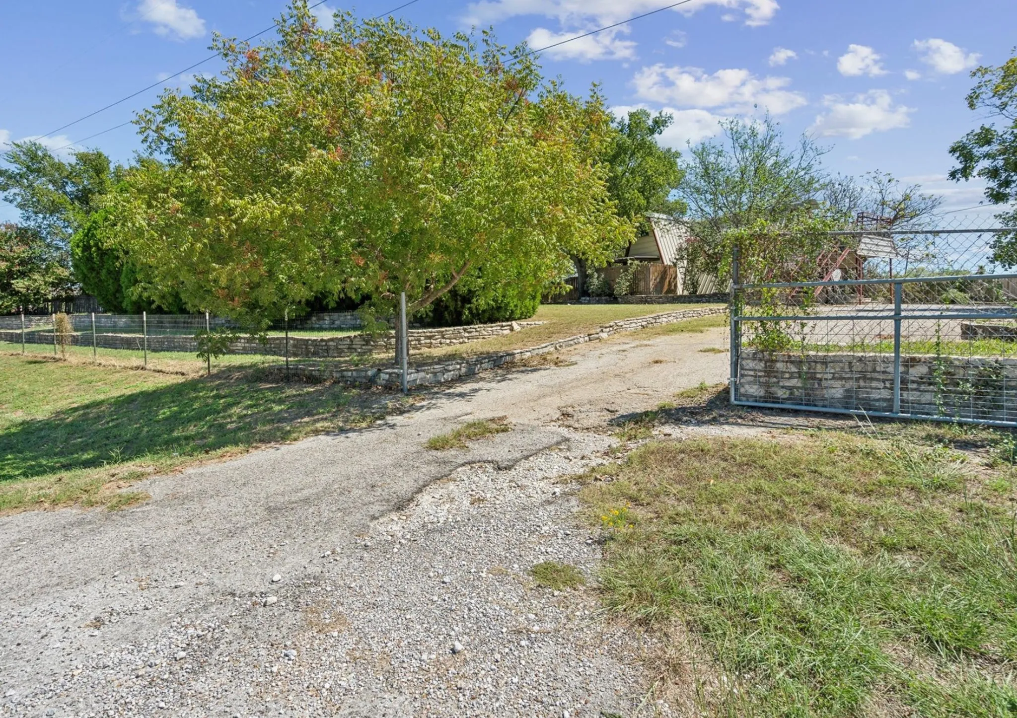 View of road with a gated entry and driveway