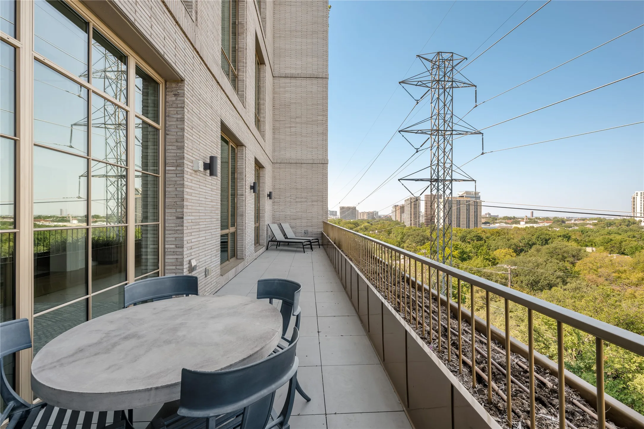 Exterior patio with tiled flooring, metal railing, and brick facade