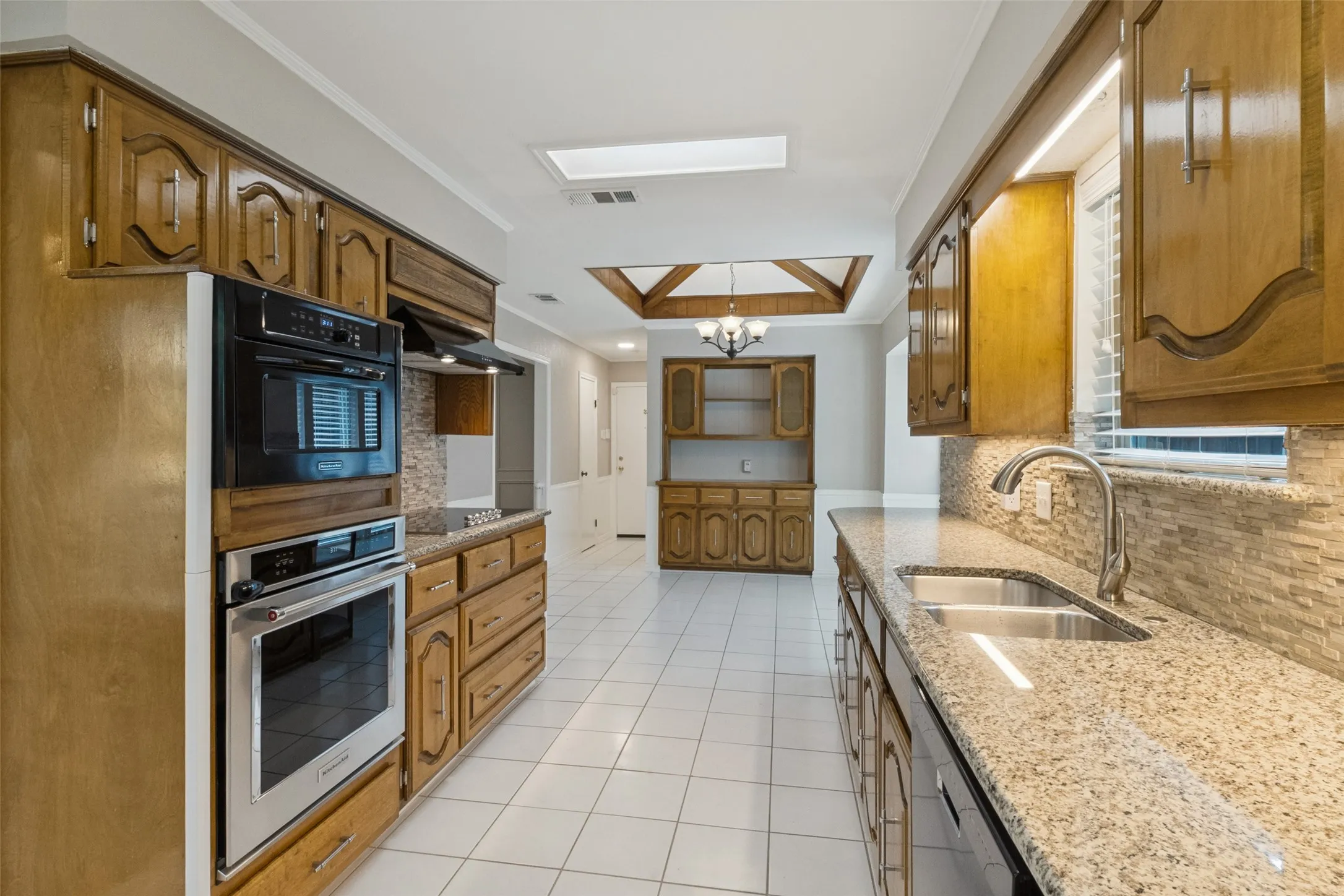 Kitchen featuring wood cabinetry, stainless steel appliances, a double basin sink, and granite countertops