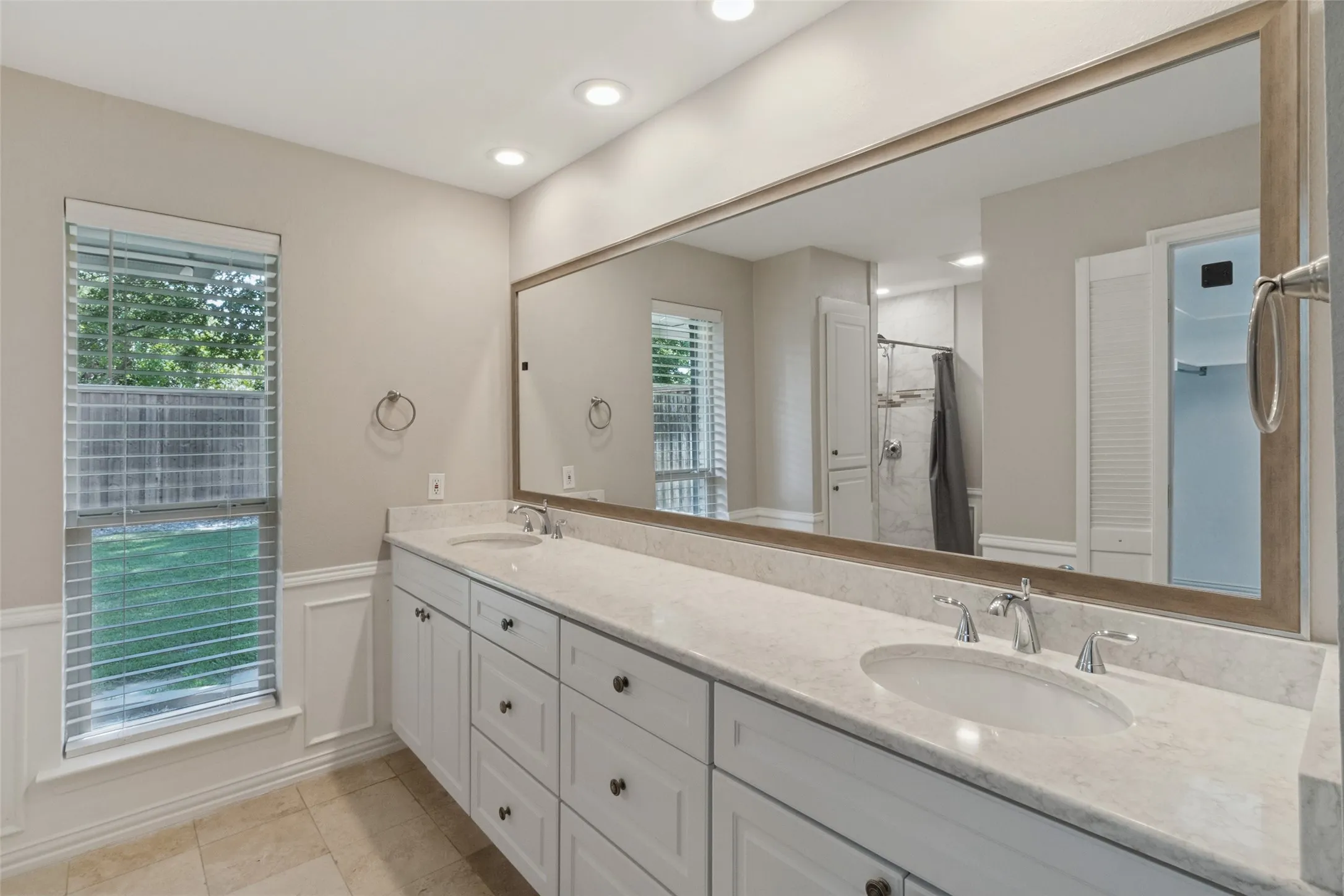 Dual vanity with integrated sinks and chrome fixtures, framed mirror, recessed lighting, and tile flooring