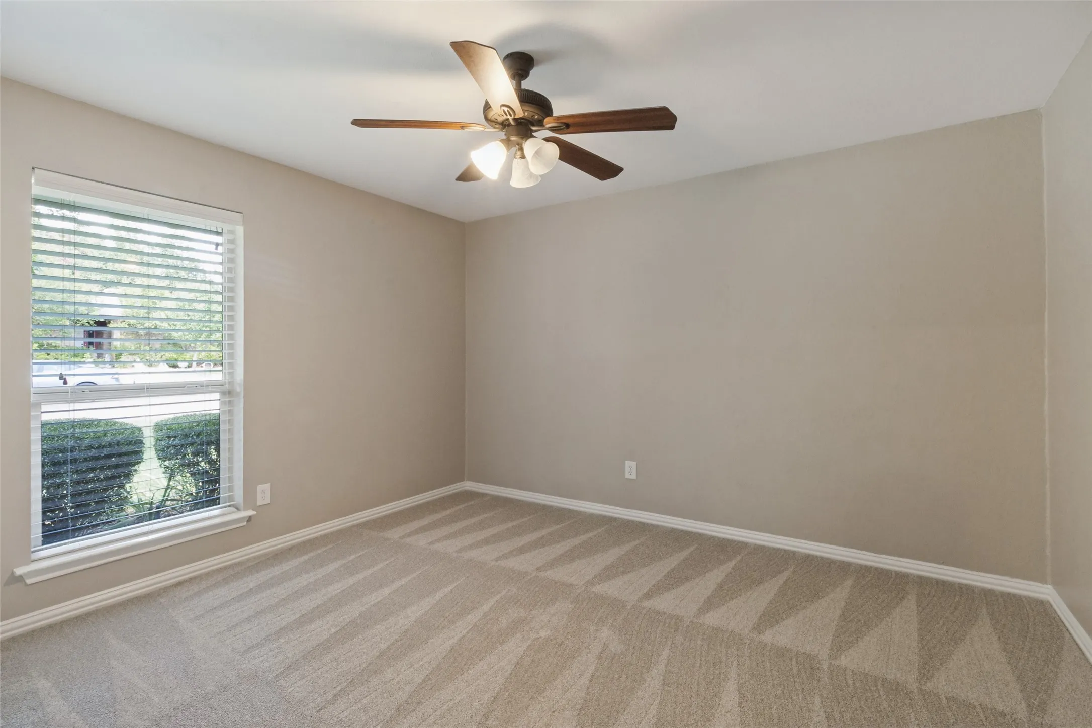 Textured carpet, neutral wall palette, ceiling fan with integrated lighting, window with blinds, and white trim