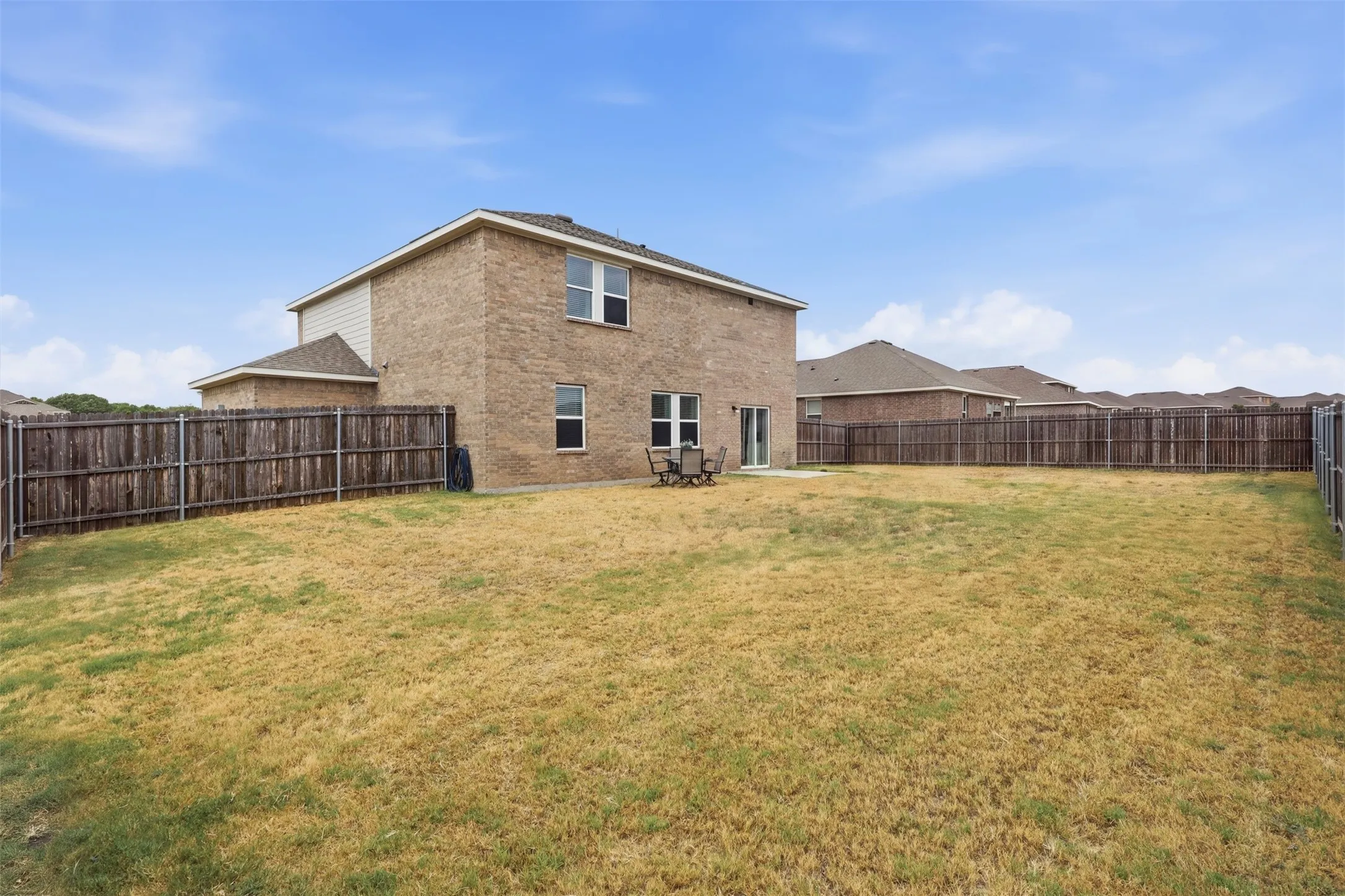 fenced backyard with a brick and siding exterior and a concrete patio