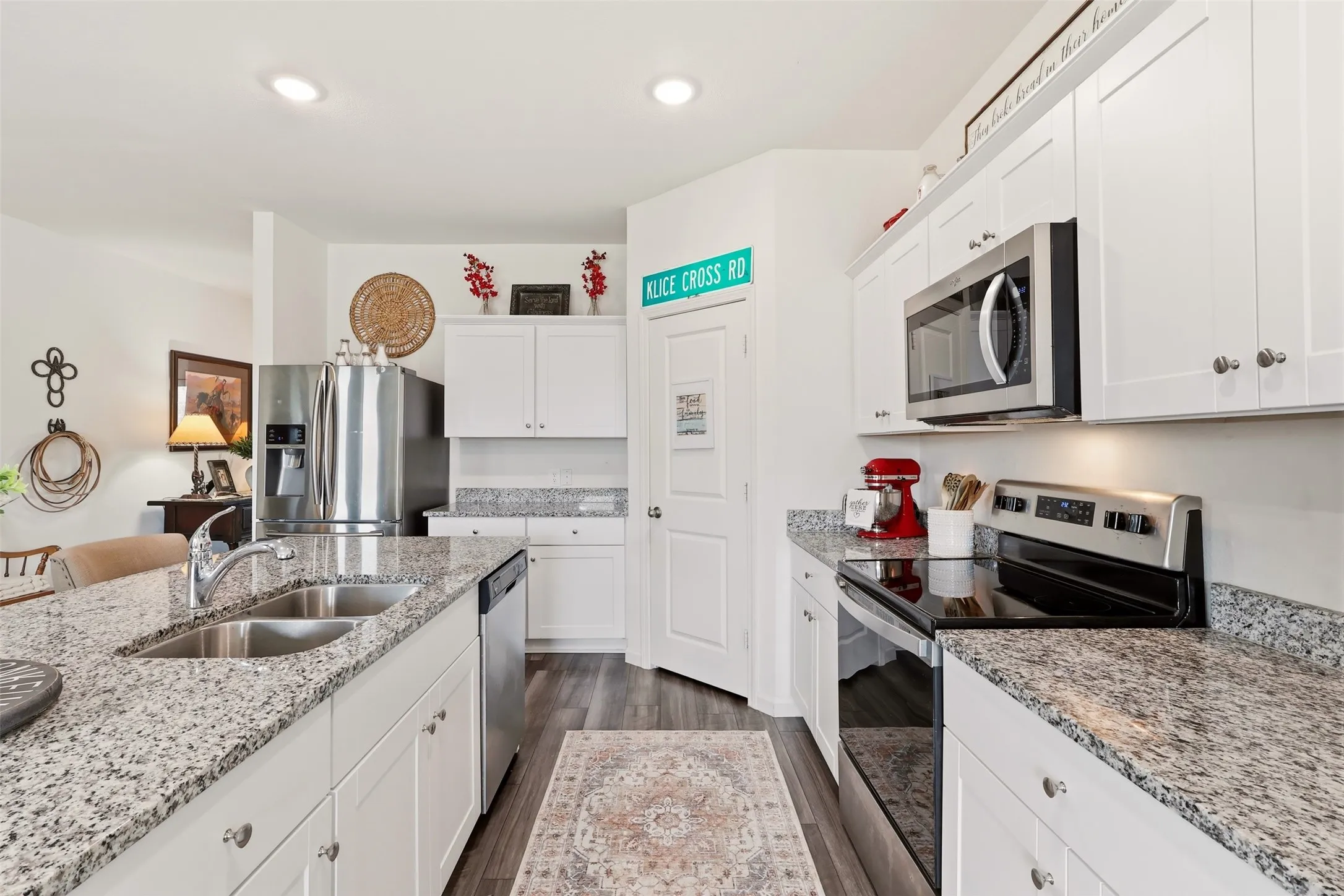 Kitchen featuring white cabinetry, granite countertops, stainless steel appliances, a double basin sink, and wood-finish flooring