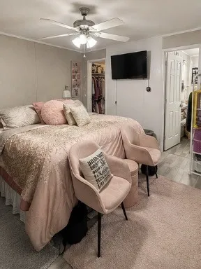 Ceiling fan with integrated lighting, wall-mounted television, wood-finish flooring, and a closet with a white panel door