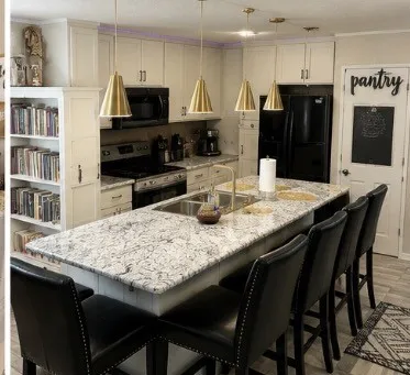Kitchen featuring an expansive island with a stainless steel sink, gold-tone faucet, and pendant lighting and seating