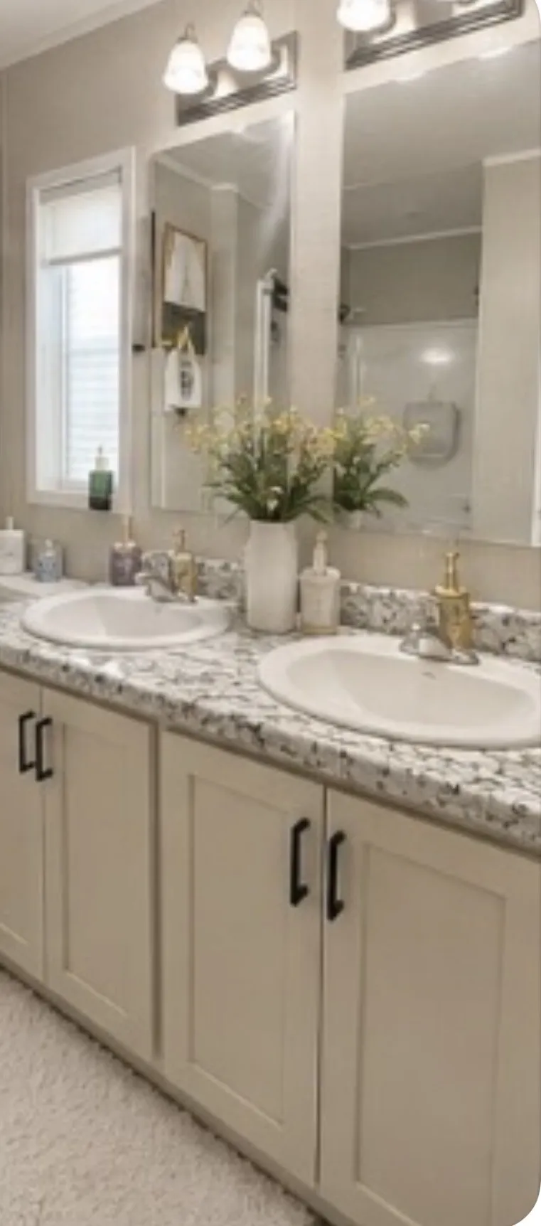 Double vanity with dual undermount sinks, speckled countertop, and light-toned cabinetry with dark hardware