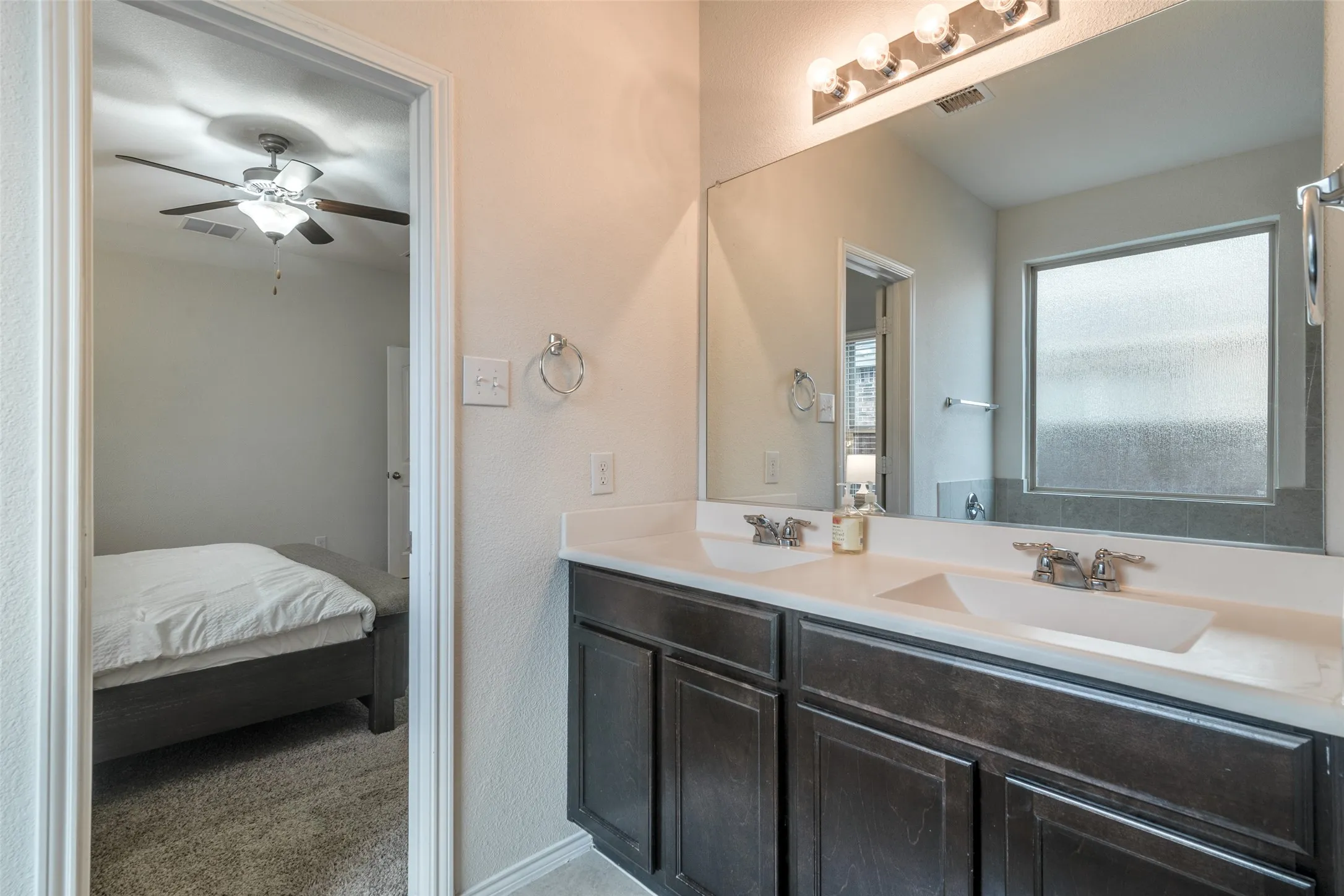 Dual vanity with dark wood-finish cabinetry and white countertops