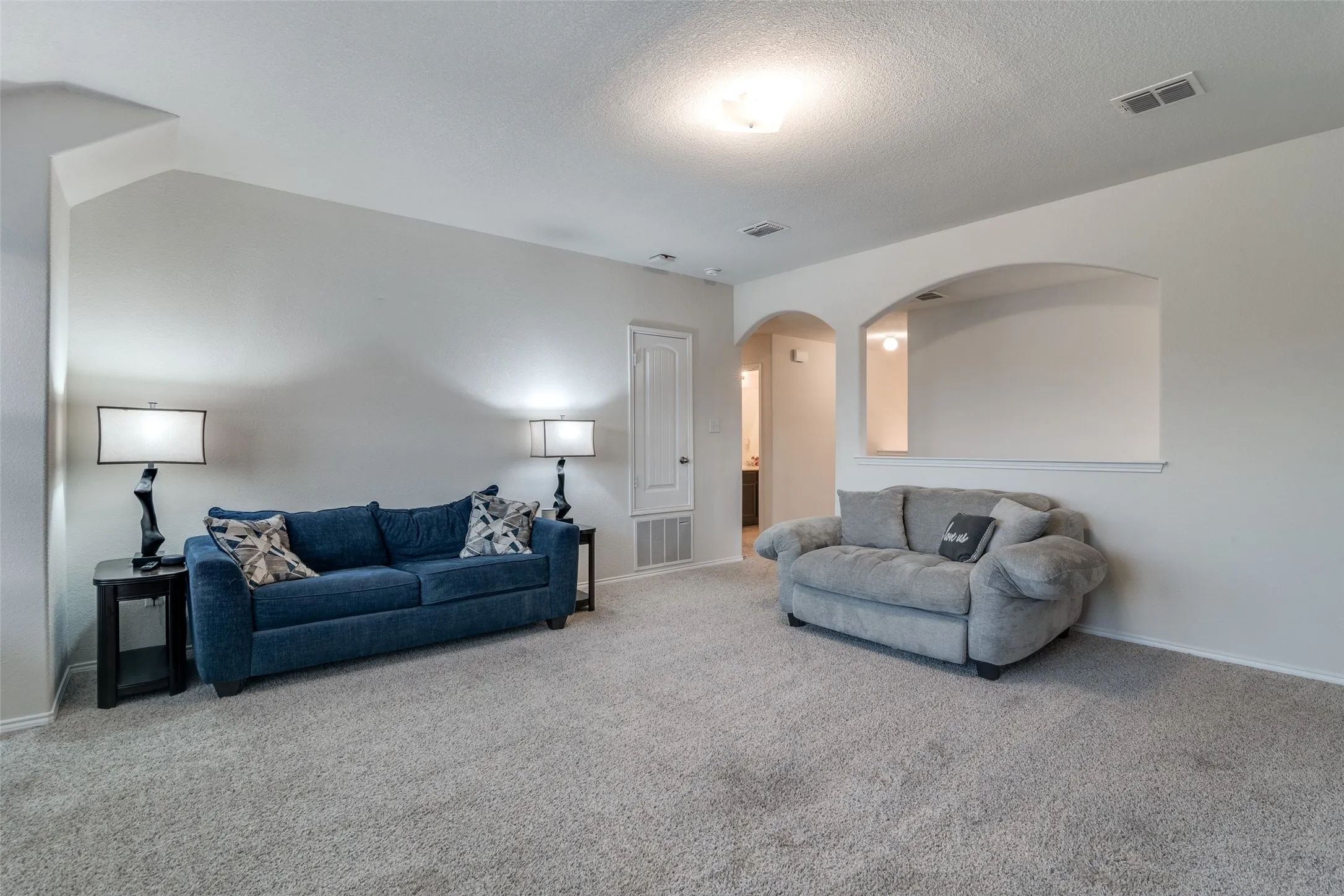 Spacious room with light neutral wall tones, textured ceiling, and plush carpeting