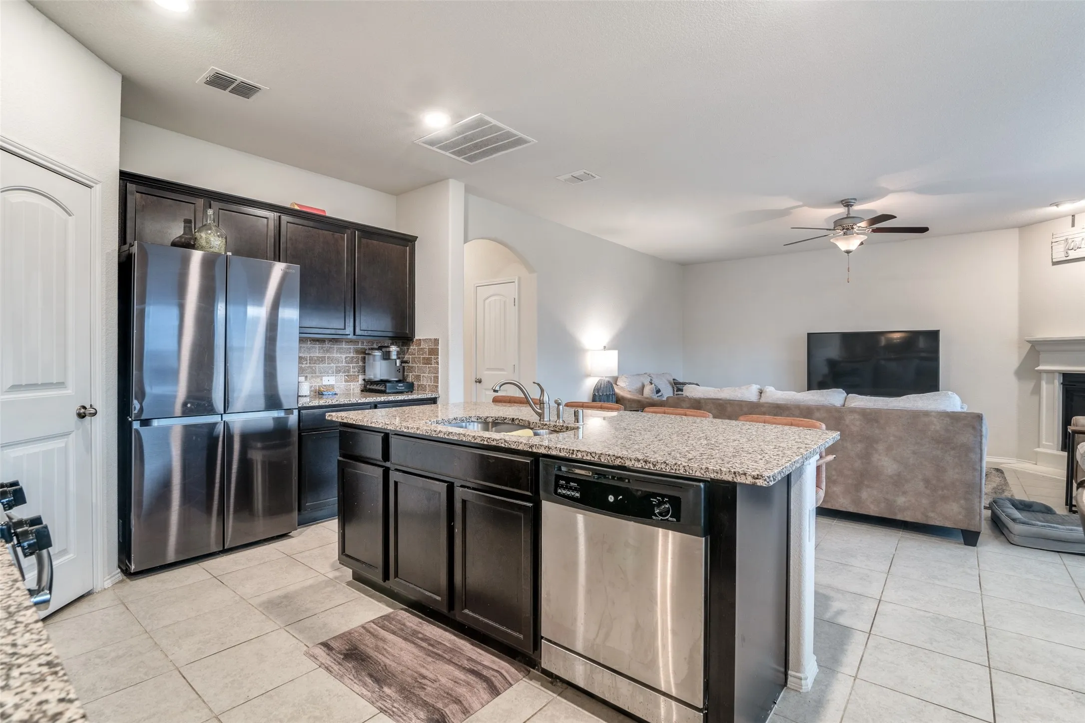 Kitchen featuring dark wood cabinetry, a stainless steel French door refrigerator, and a stone-look backsplash