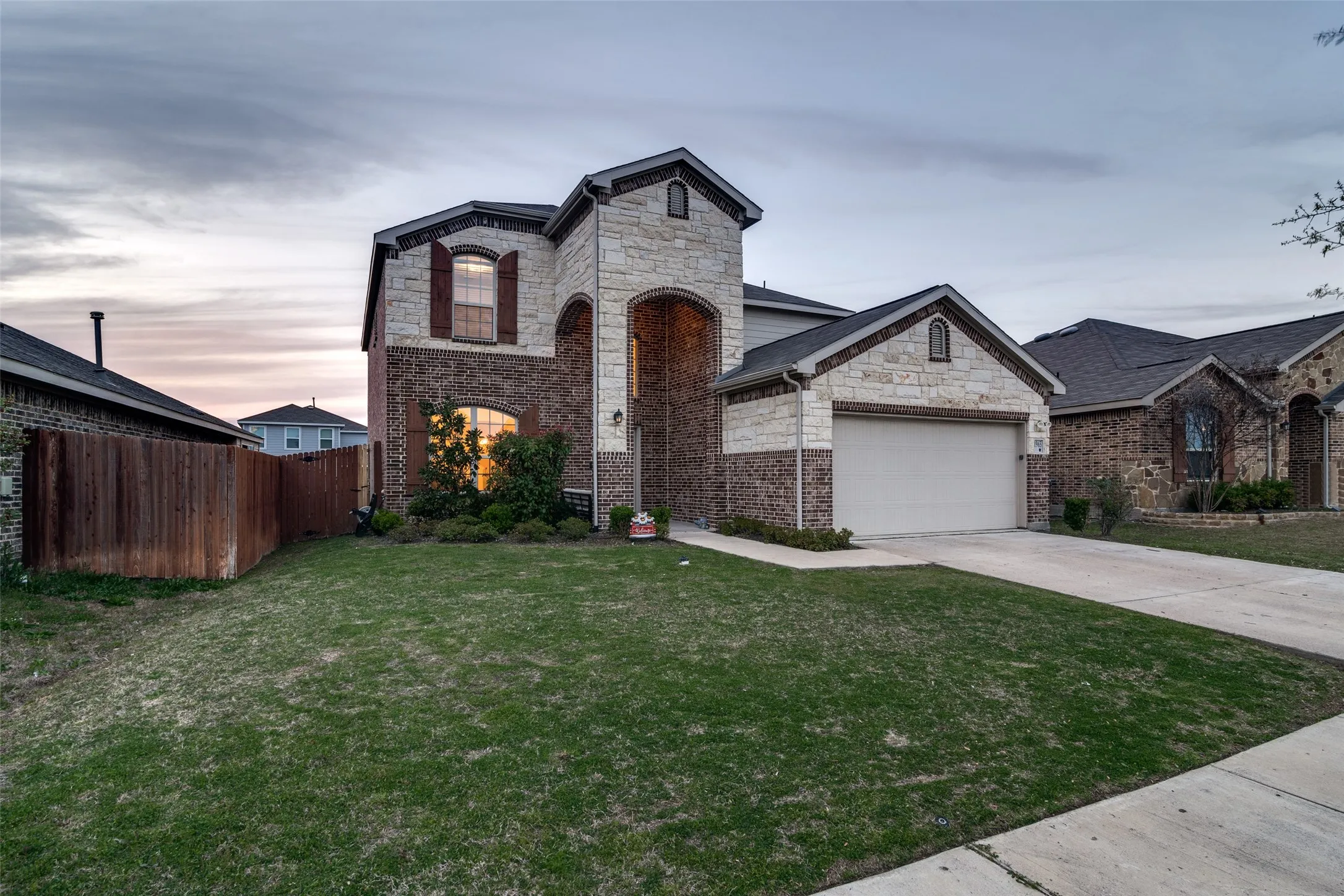Two-story residence featuring brick and stone veneer, a two-car garage, and a concrete driveway
