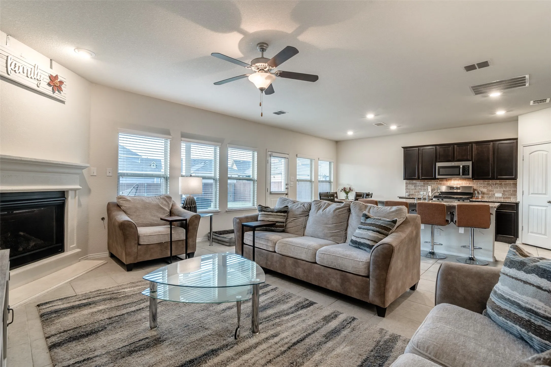 Open-concept living space featuring a fireplace, multiple windows with blinds, recessed lighting, and a ceiling fan