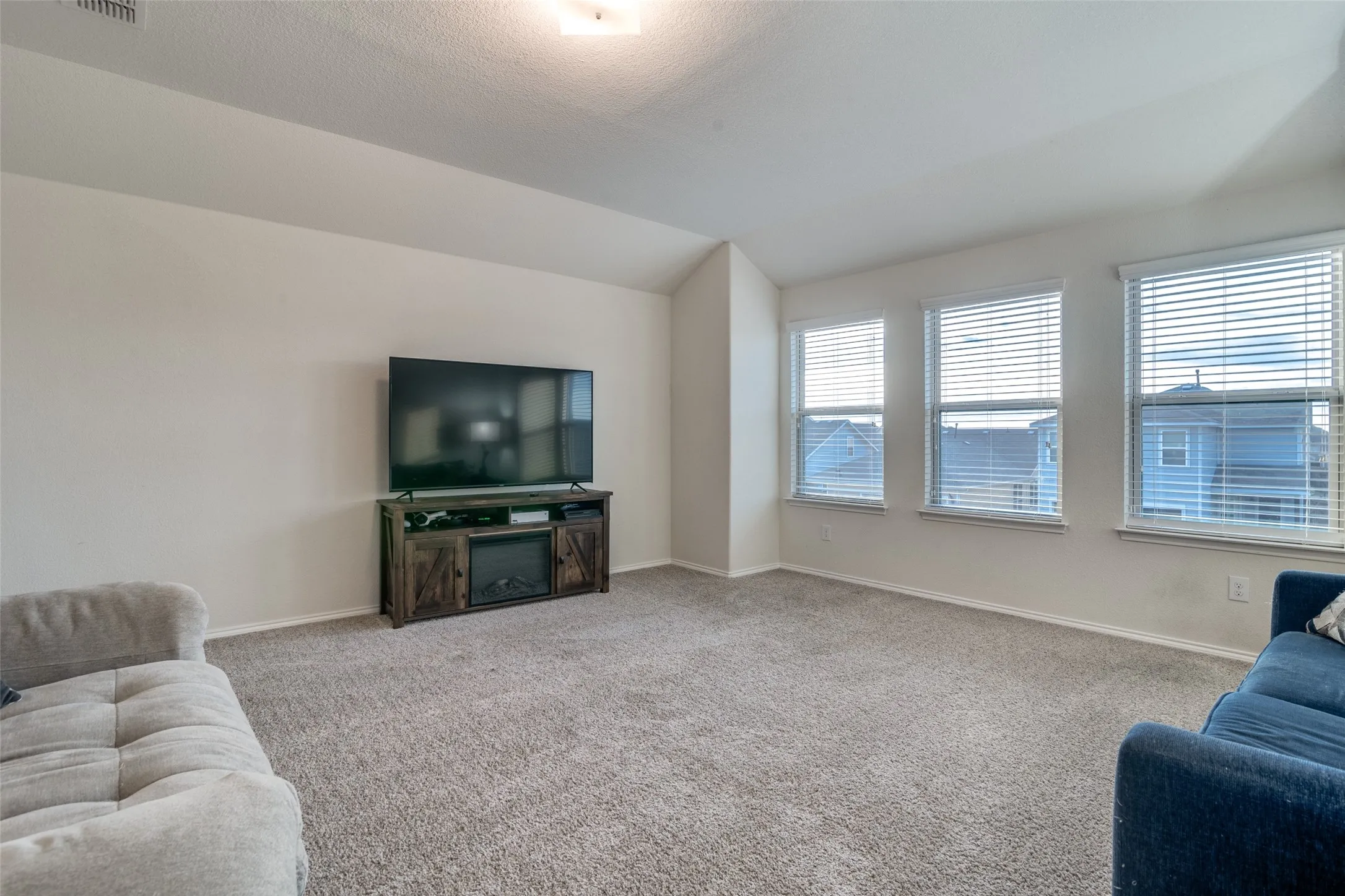 Spacious room featuring carpet flooring, neutral painted walls, and multiple windows