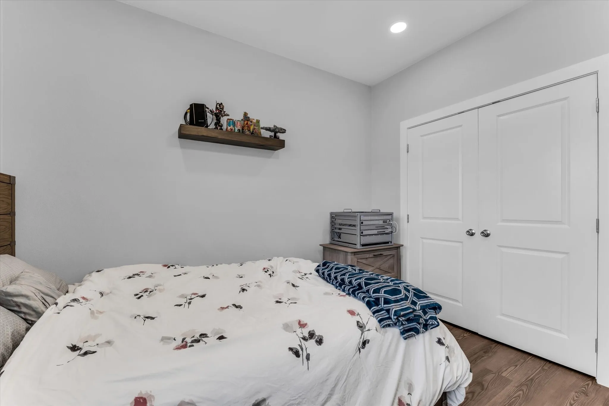 Recessed ceiling lighting, wood-finish flooring, and white bi-fold closet doors