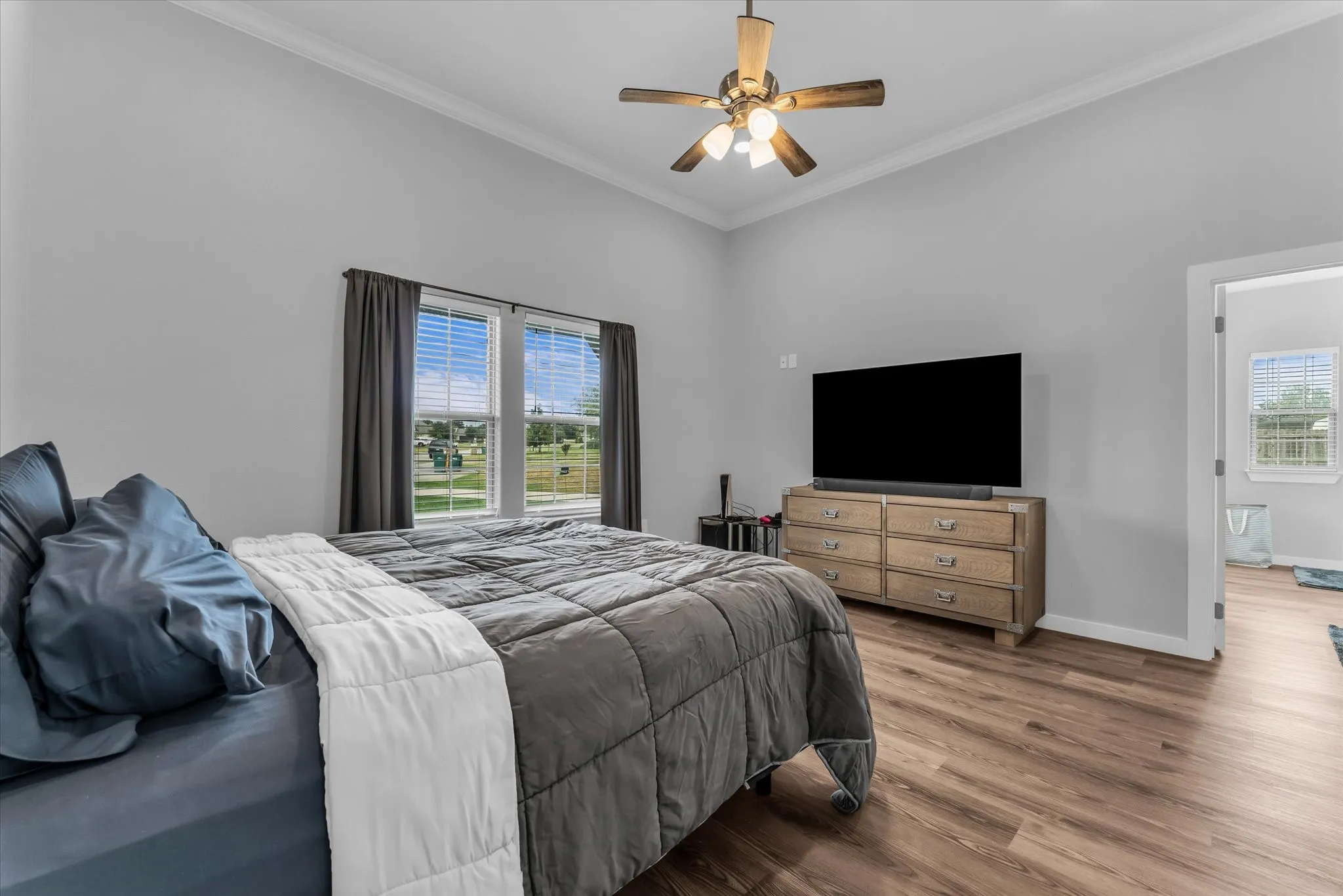 Vaulted ceiling with crown molding, wood-finish flooring, and a ceiling fan with integrated lighting