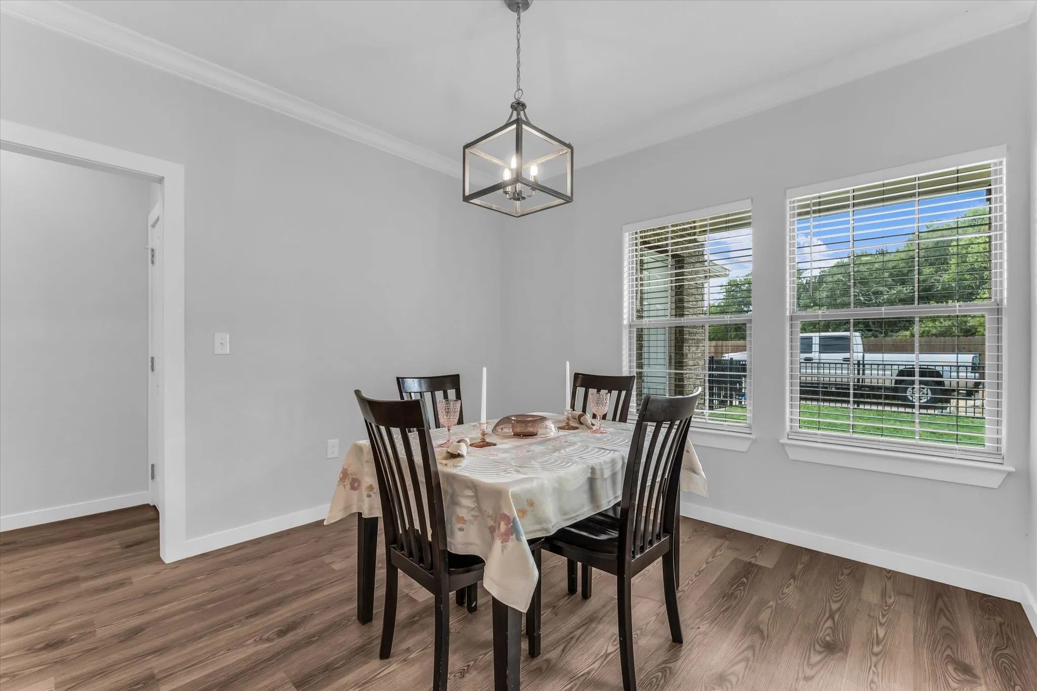 Wood-finish flooring, crown molding, and a modern geometric light fixture