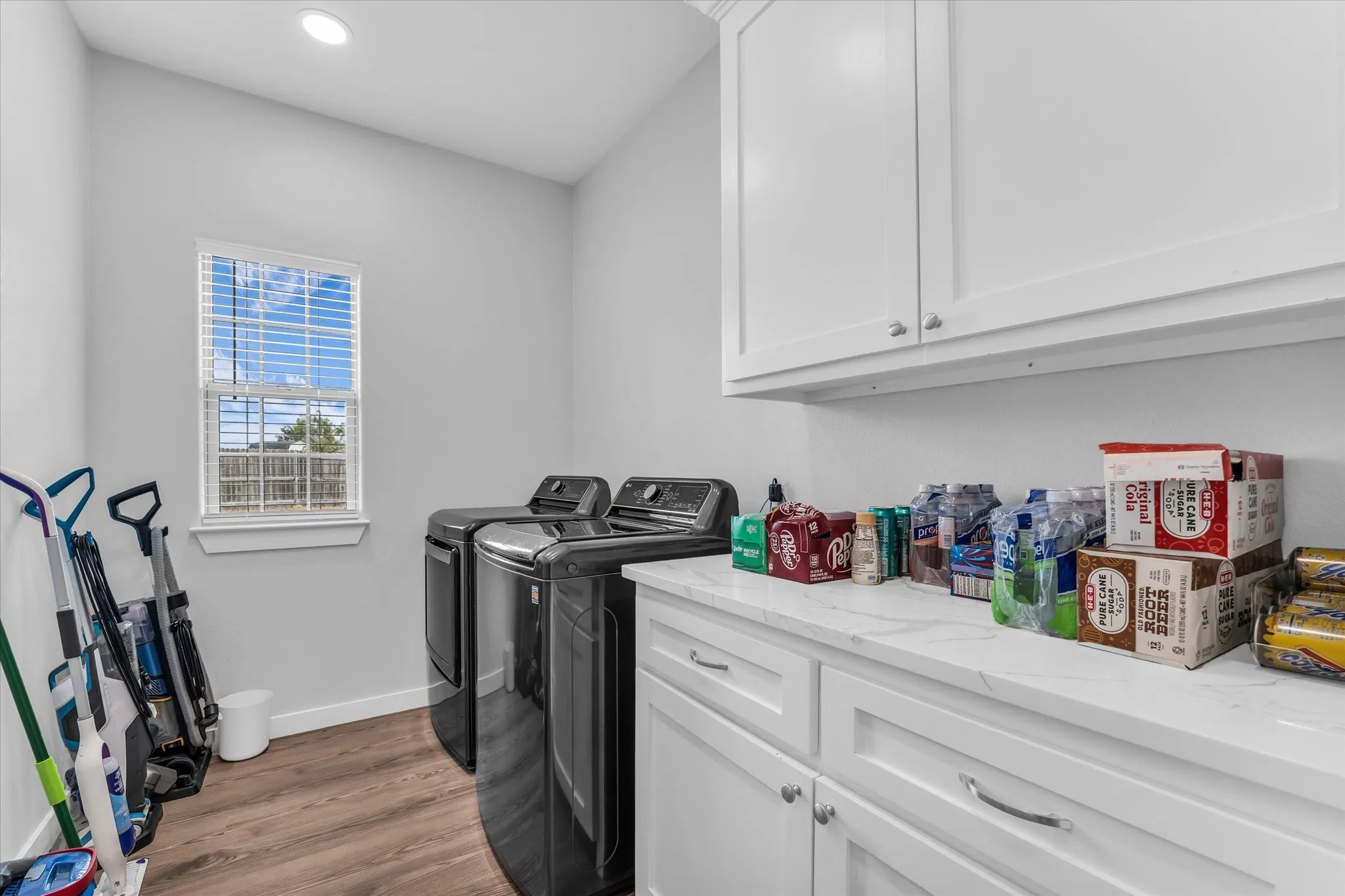 White shaker cabinetry with chrome hardware, a white countertop, and wood-finish flooring