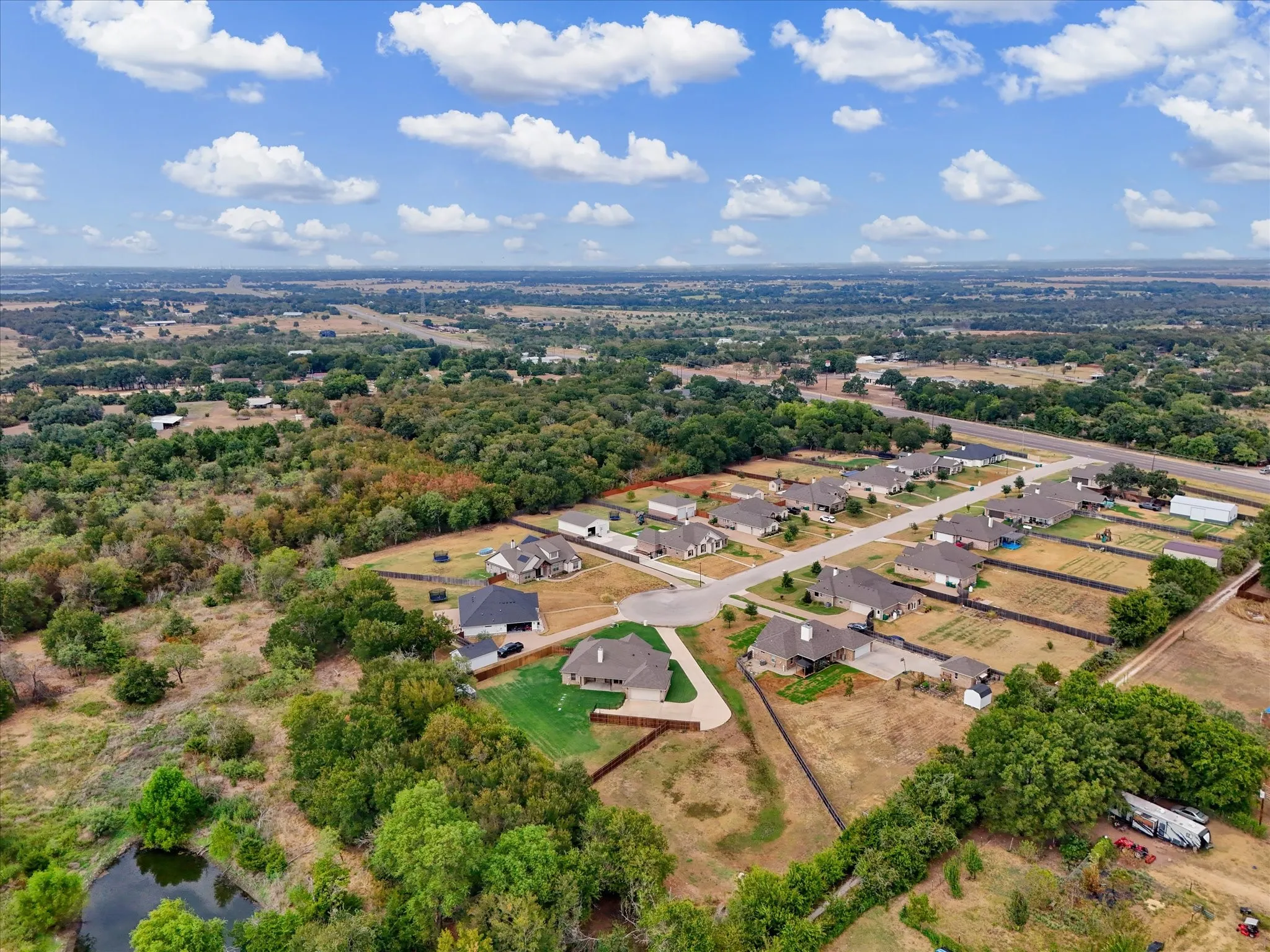 Aerial community perspective with a cul-de-sac, residential properties, and surrounding wooded areas