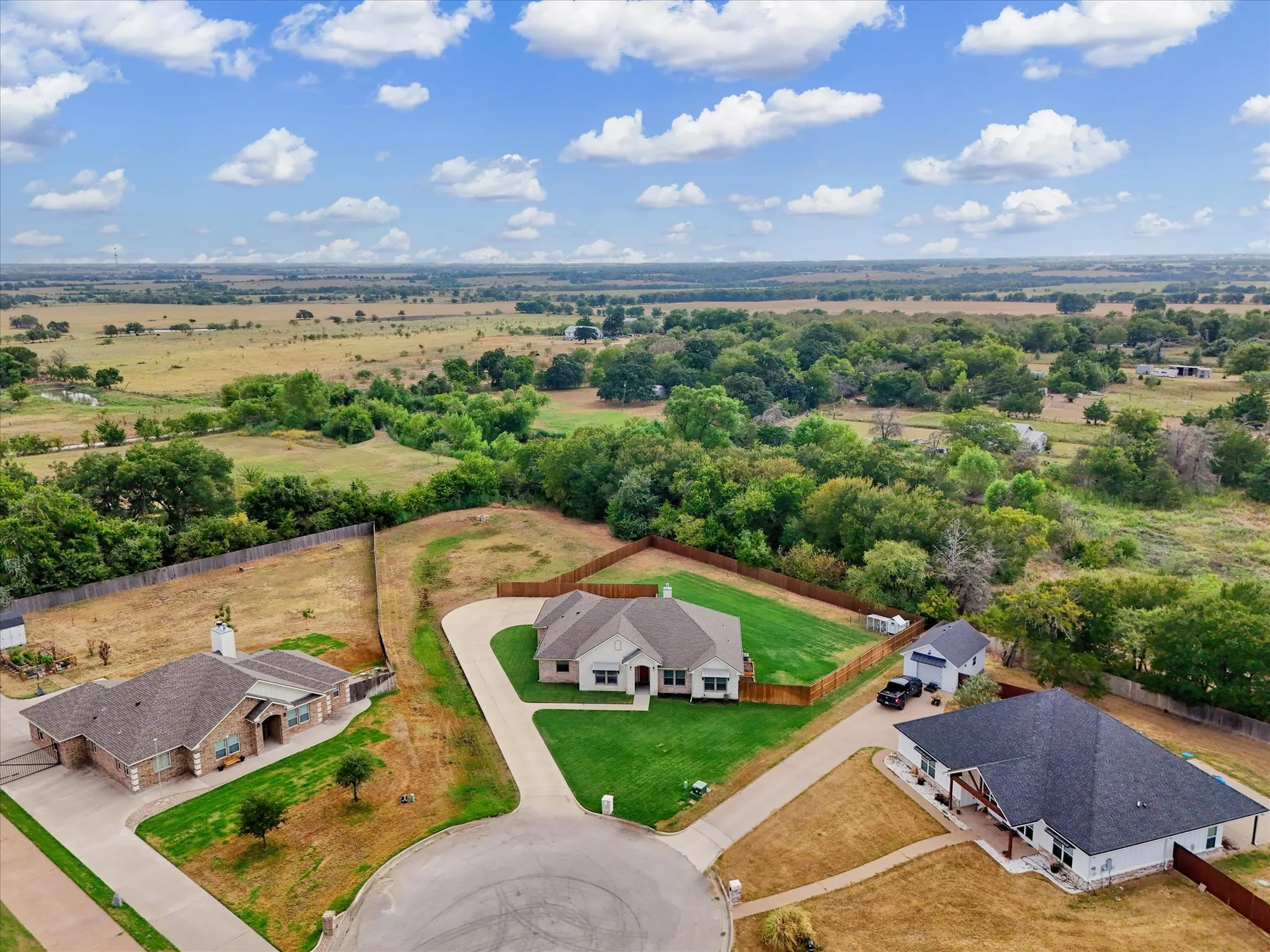 Single-story residence featuring a gray shingle roof, light-toned exterior, and a fenced backyard