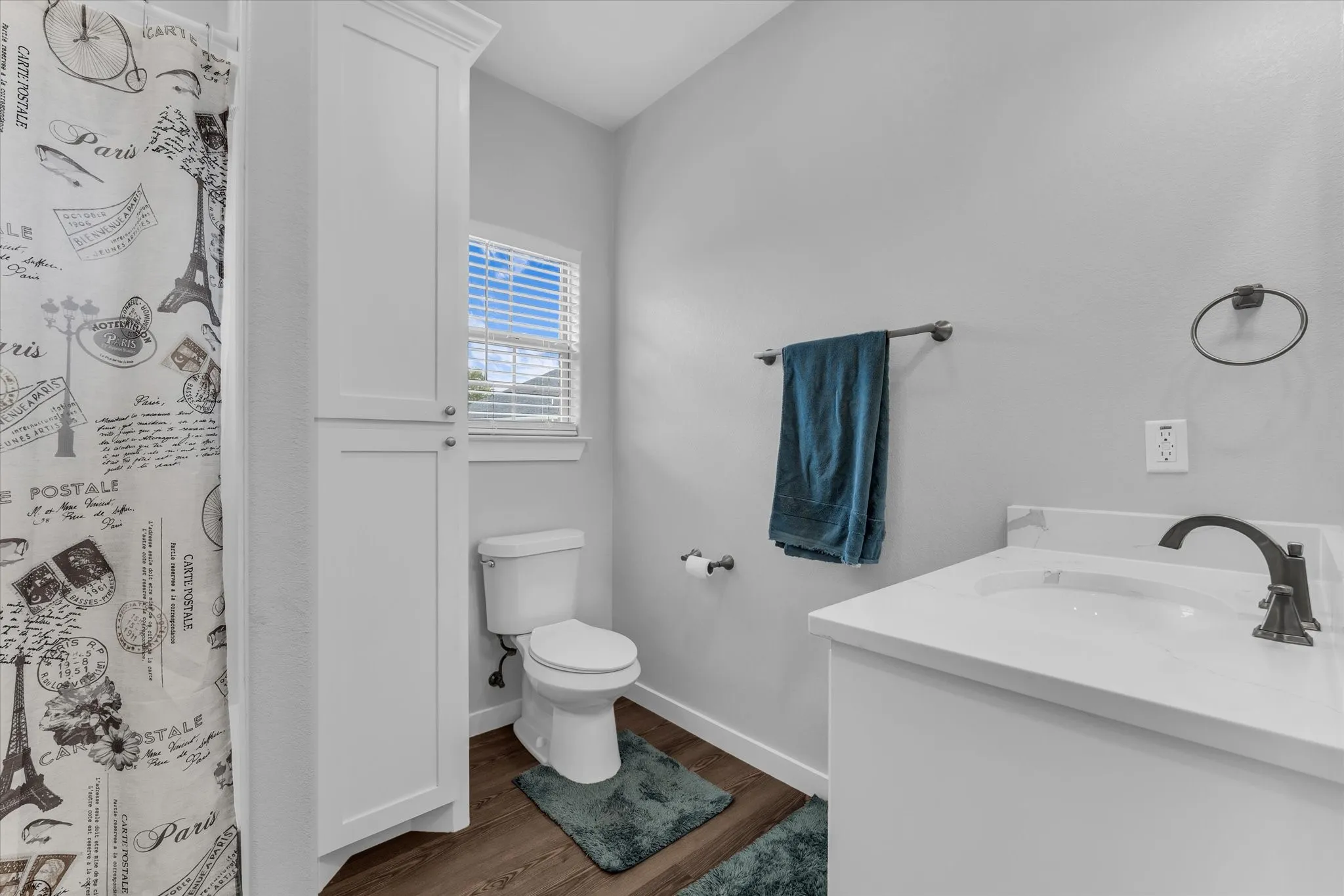 White vanity with integrated sink, dark bronze faucet, and wood-finish flooring