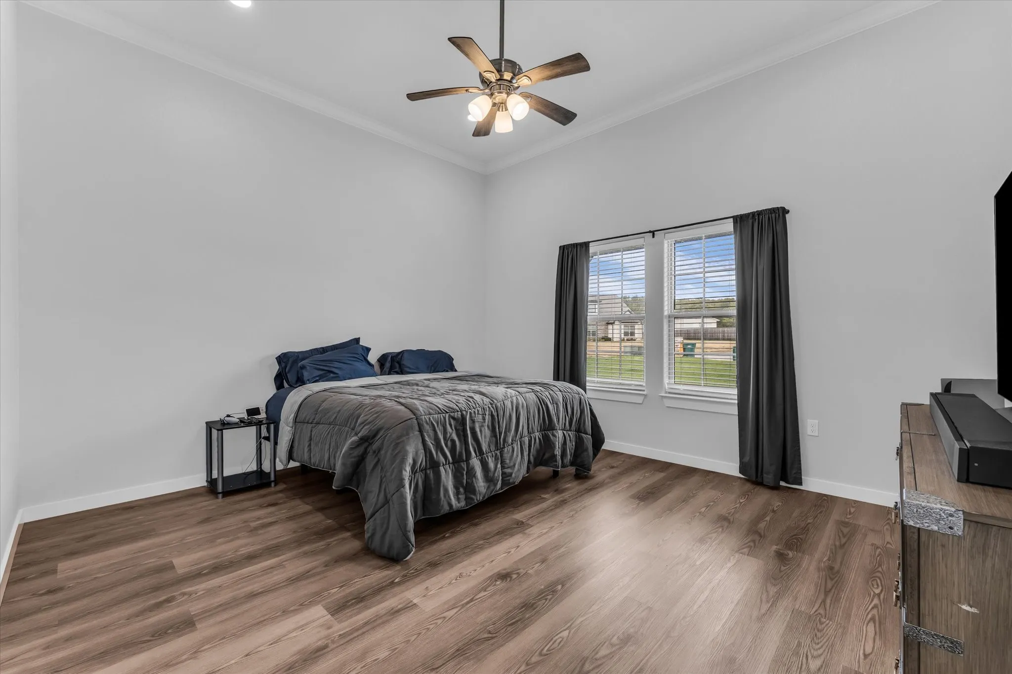 Vaulted ceiling featuring a ceiling fan with integrated lighting, wood-finish flooring, and white trim