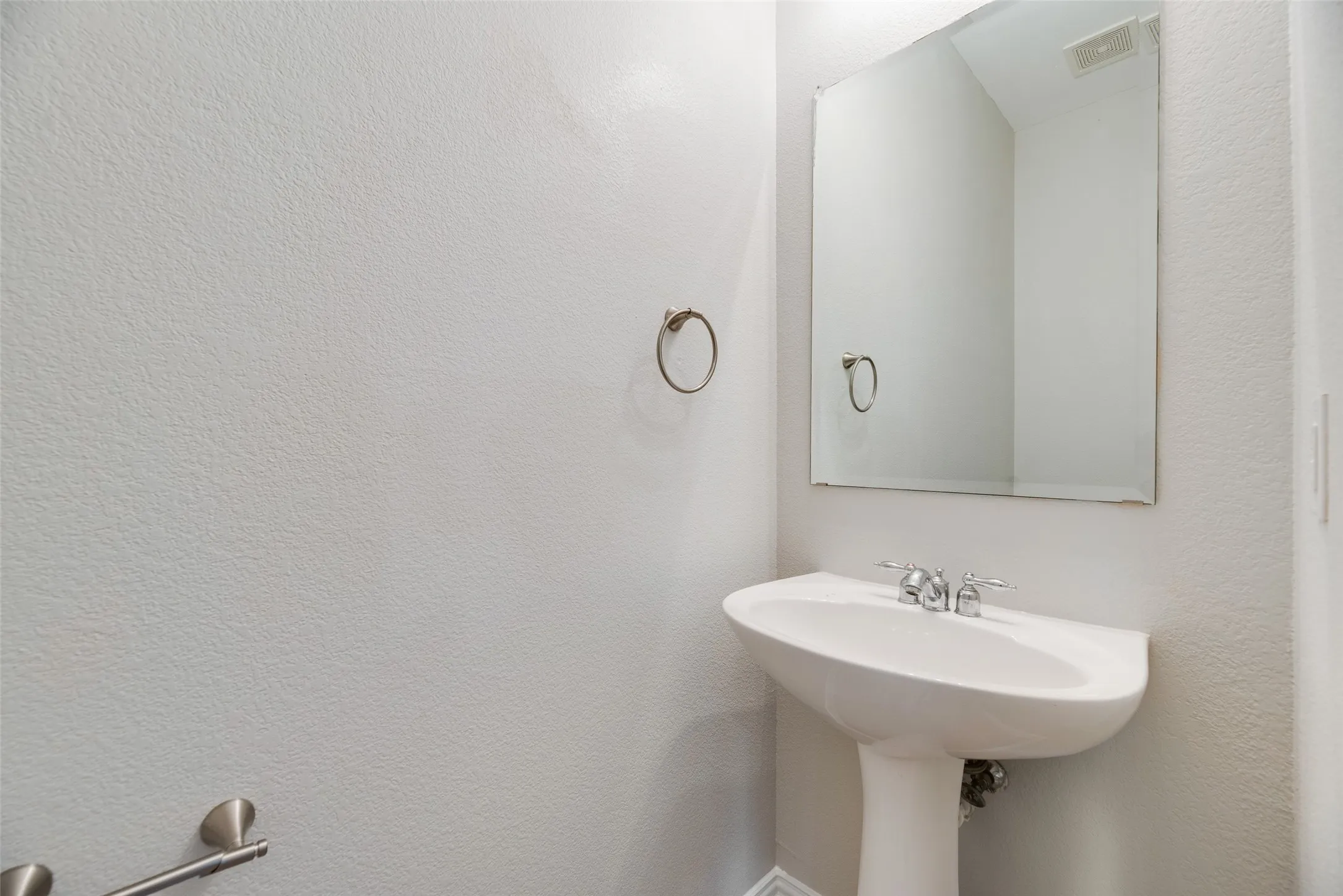 Pedestal sink with chrome faucet, large wall mirror, and towel ring