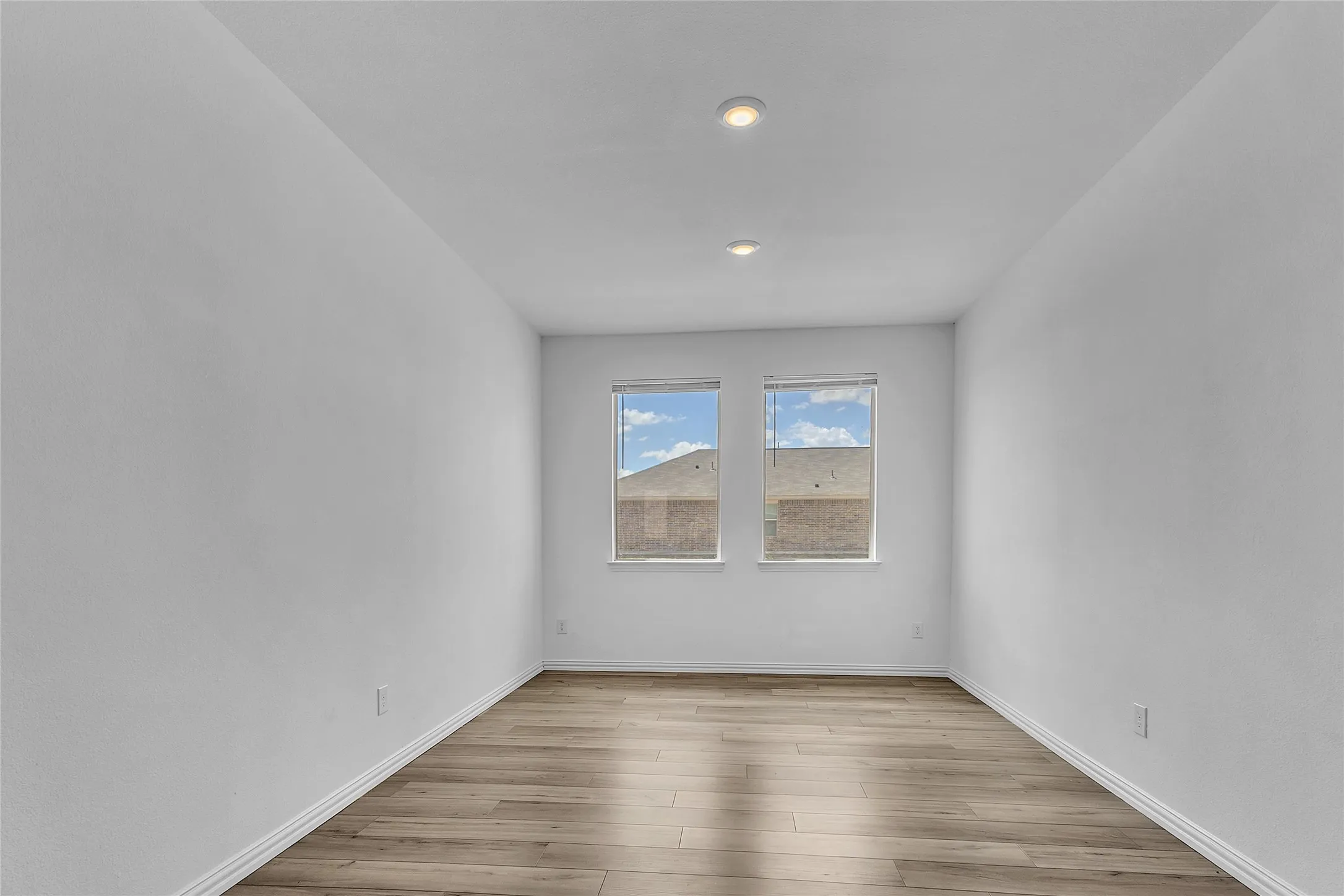 Dining room with recessed lighting, two windows with blinds, and wood-look flooring in this Forney single-story home