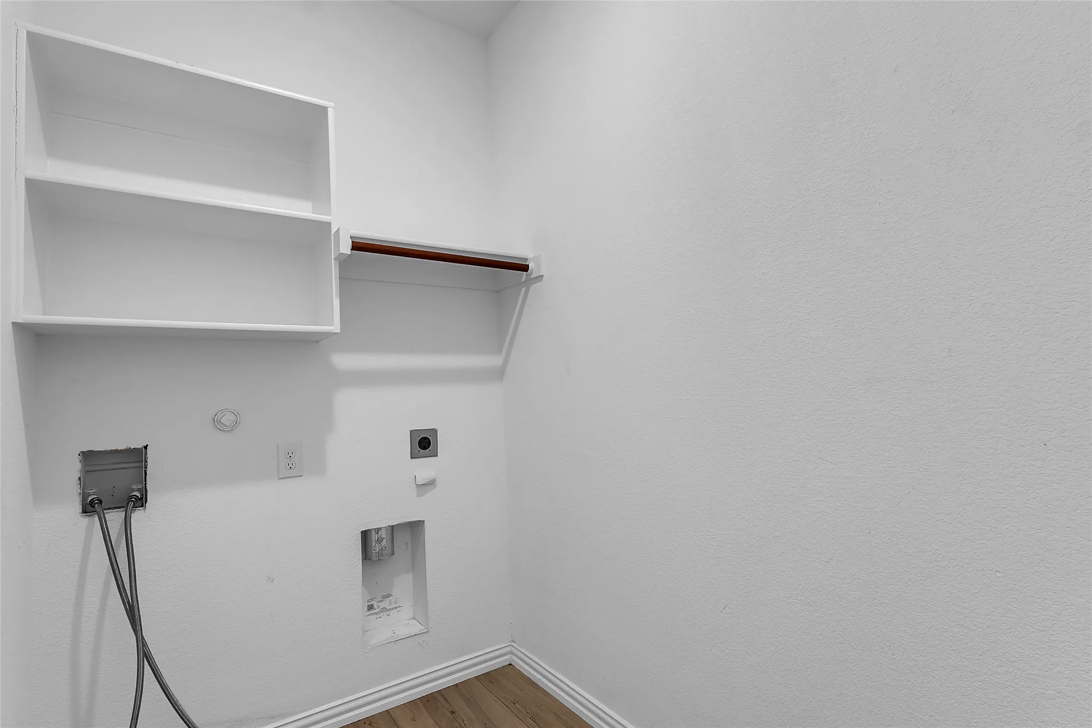 Laundry room with washer and dryer connections, a wall shelf with hanging rod, and wood-look flooring