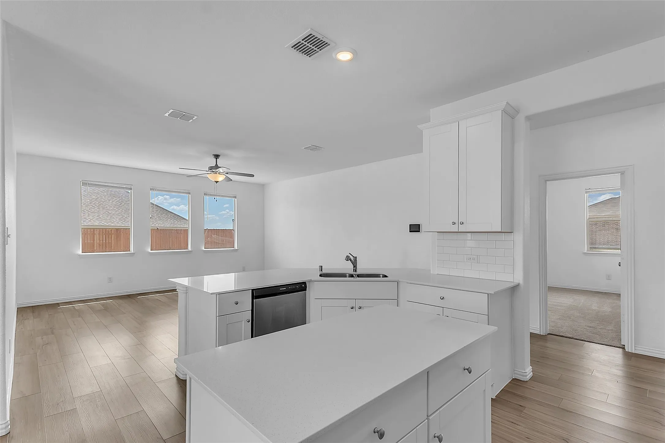 Center island and sink peninsula open to the living room, with a doorway to the carpeted primary​​‌​​​​‌​​‌‌​‌‌​​​‌‌​‌​‌​‌​​​‌​​ bedroom