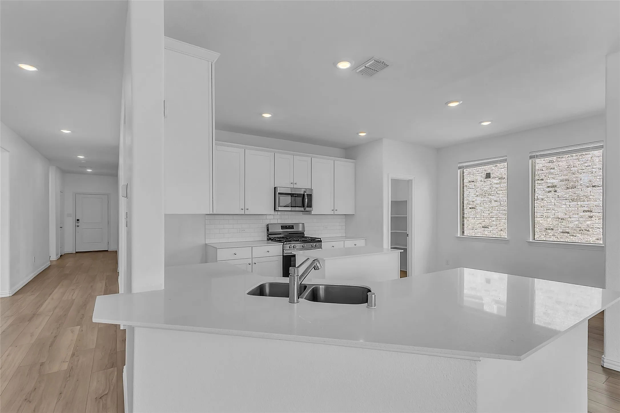 Kitchen peninsula looking toward the breakfast nook, pantry, and front hallway, with recessed lighting throughout