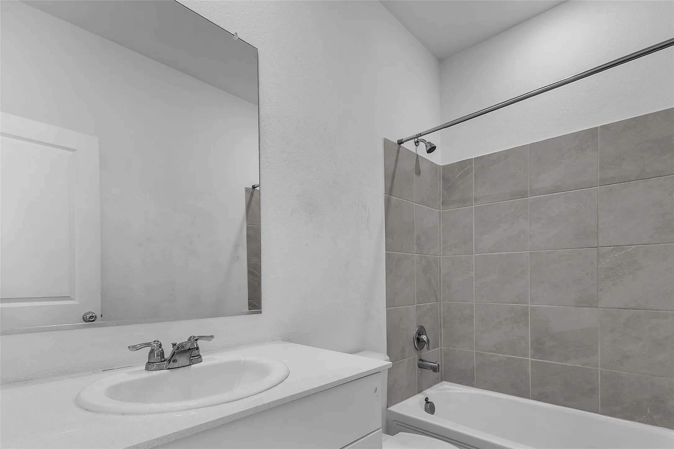 Secondary full bath with a tub and shower combo, gray tile surround, and a single-sink vanity